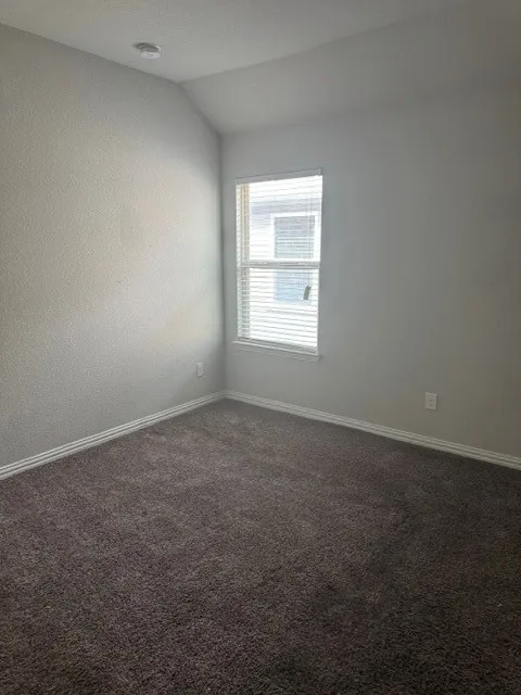 Carpeted room featuring a single window with blinds, a vaulted ceiling, and recessed lighting