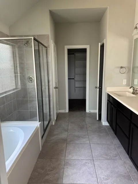 Bathroom featuring a vanity with an integrated sink, built-in cabinetry, and a shower-over-tub combination with a glass enclosure