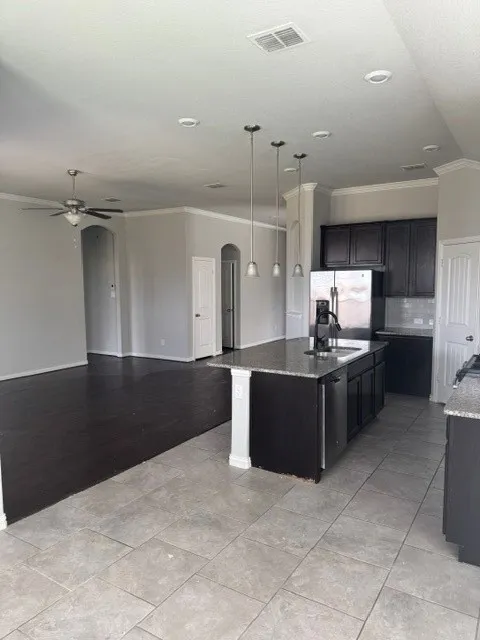 Kitchen island with a granite countertop, undermount sink, and pendant lighting