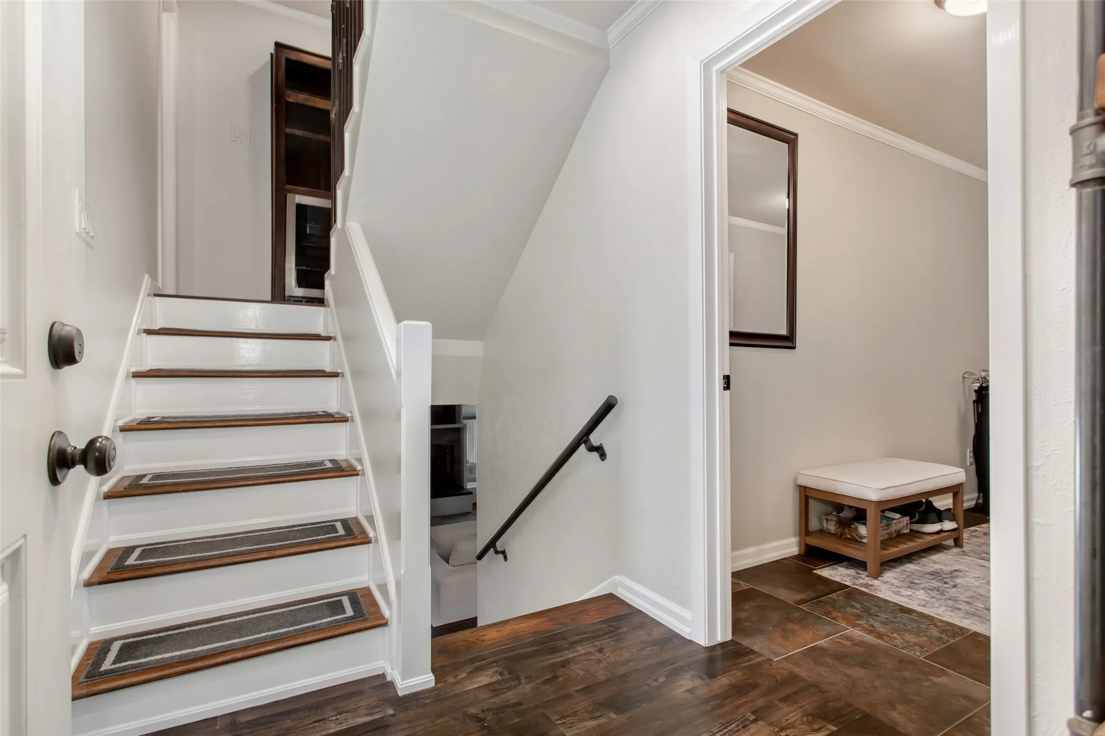 Staircase with white risers and wood-finish treads, dark wood-finish flooring, and crown molding