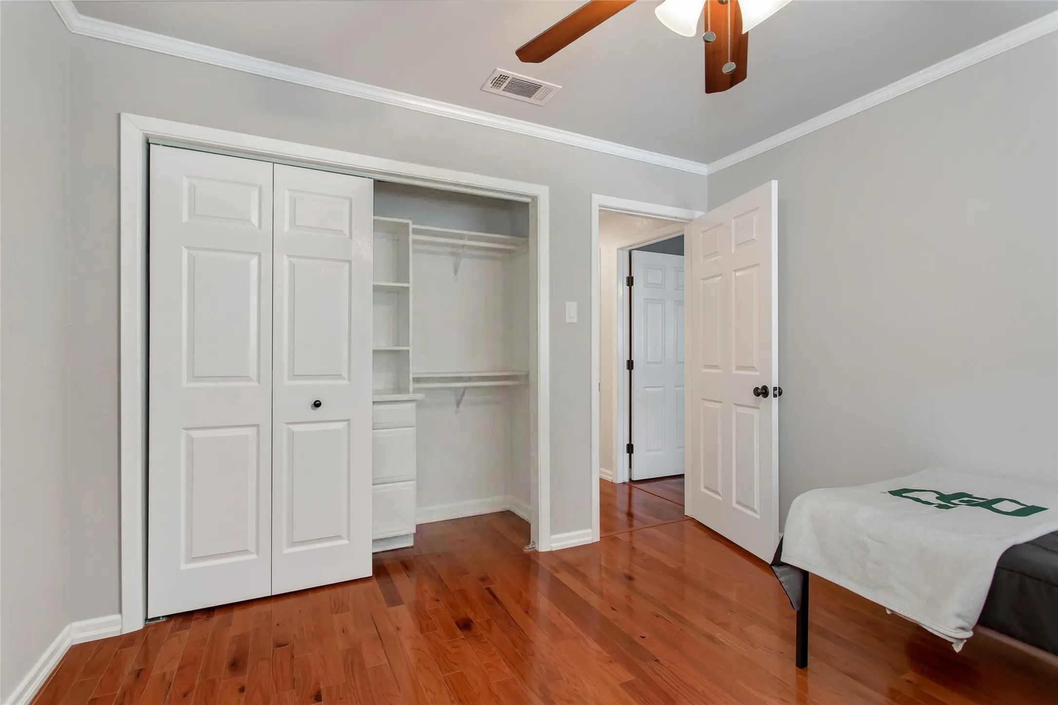 Hardwood flooring, crown molding, ceiling fan, bi-fold closet doors, and built-in closet organization