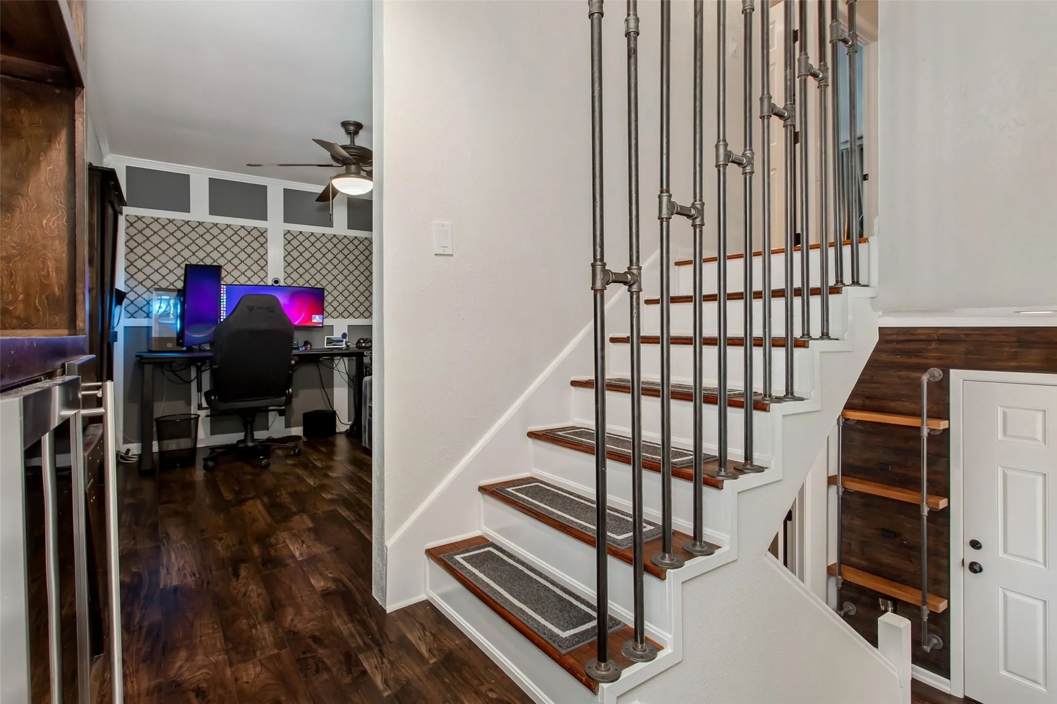 Modern staircase featuring dark wood treads, metal railings with horizontal spindles, and white painted walls with recessed lighting