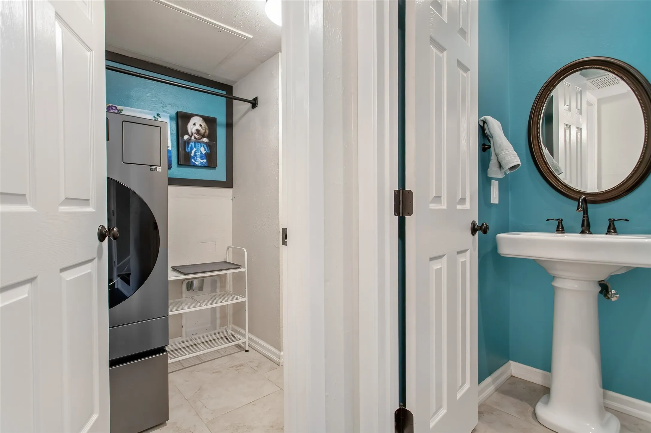 Pedestal sink with dark bronze faucet, round mirror, and tile flooring
