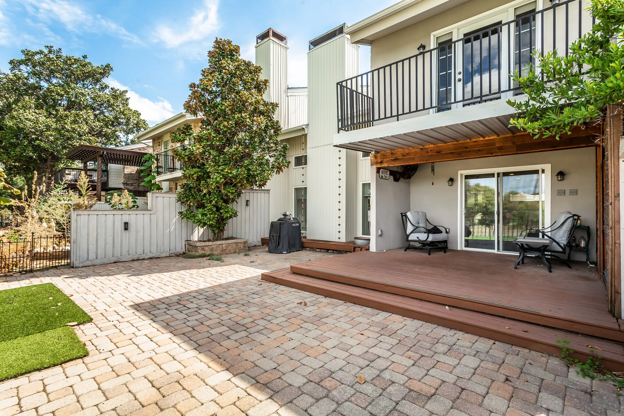 Expansive paver patio with a tiered wood-finish deck
