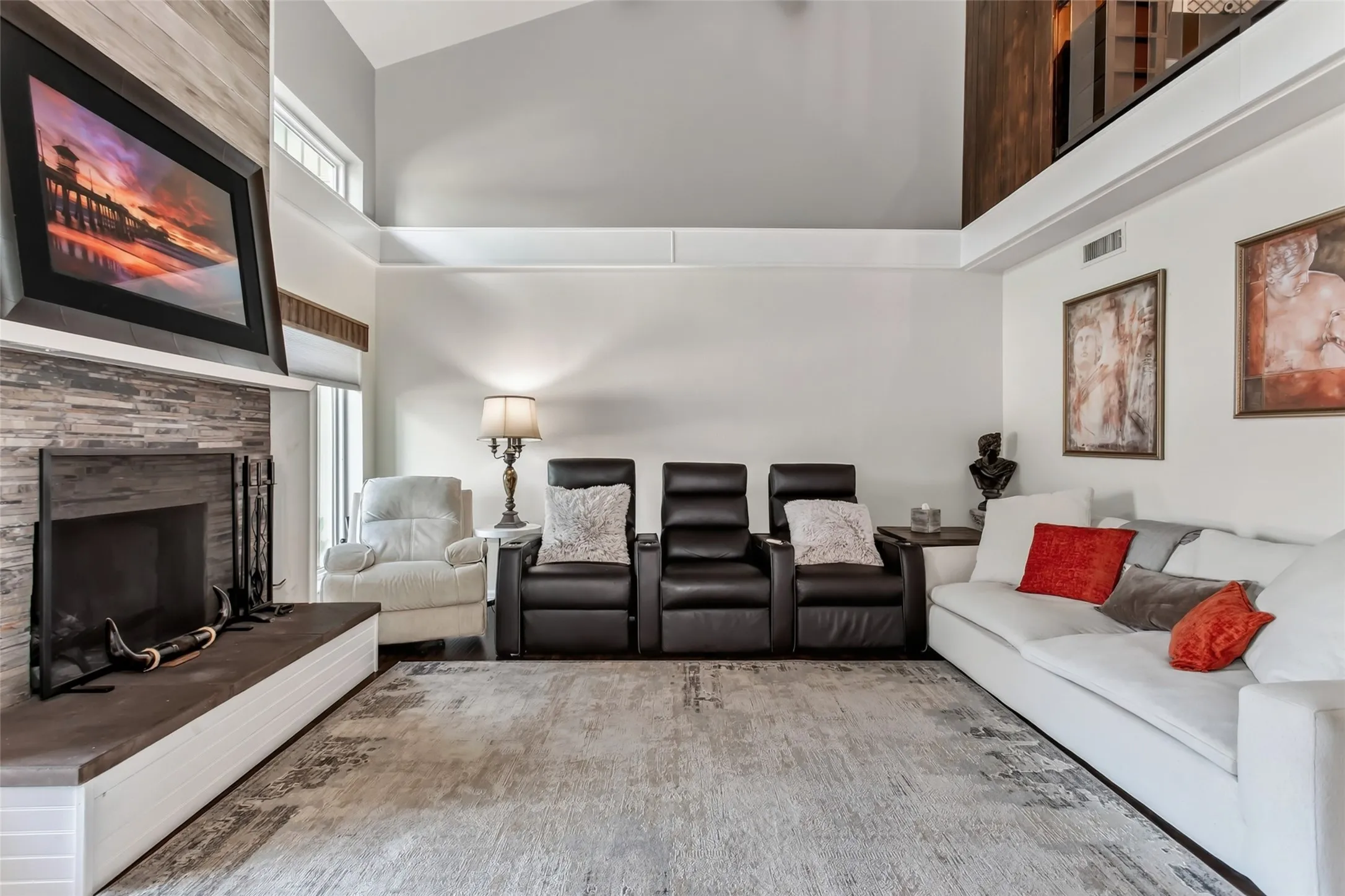 Vaulted ceiling, stone-clad fireplace, wood-finish accent wall, upper-level architectural feature, transom windows