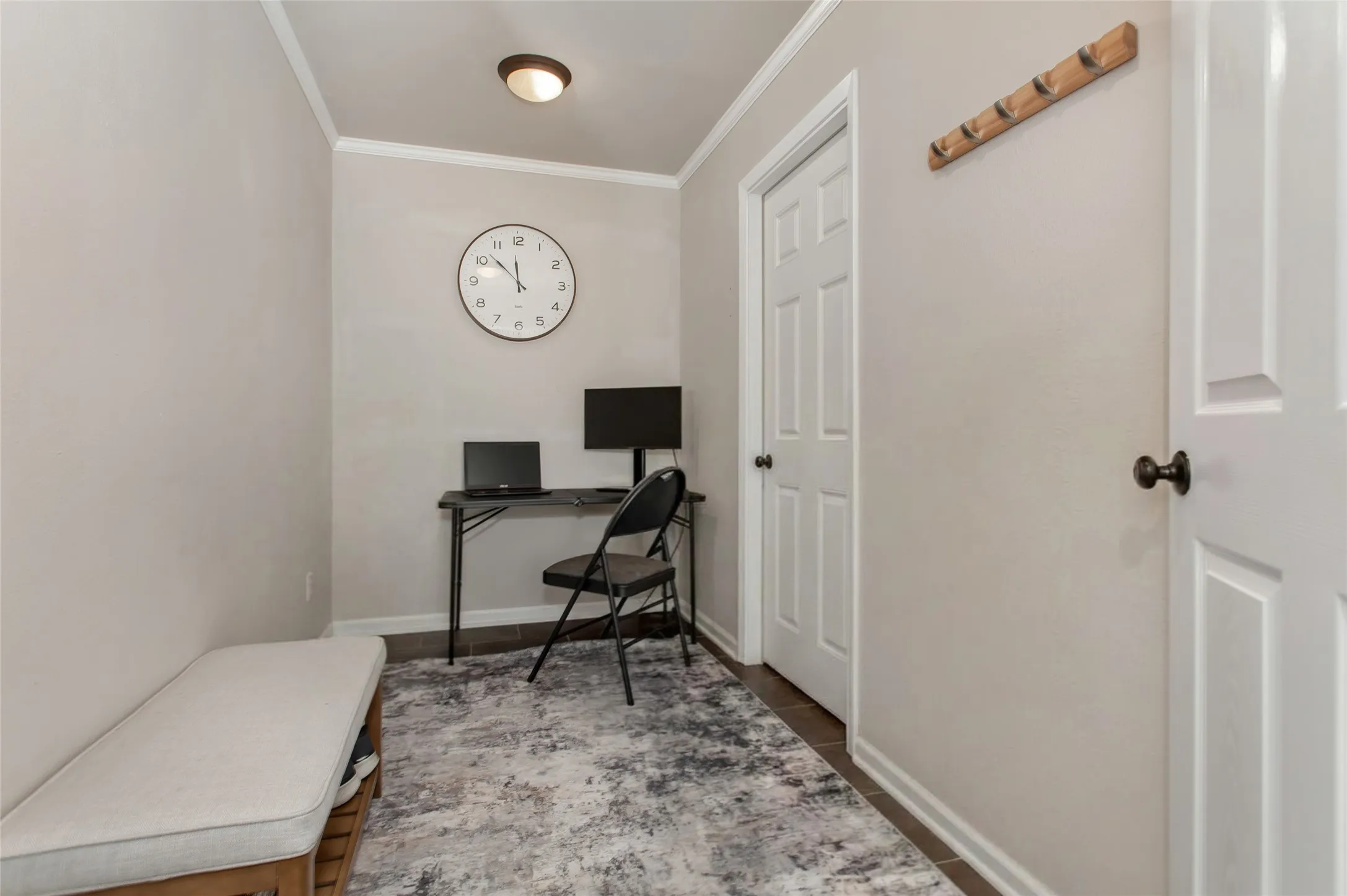 Neutral wall color, crown molding, wood-finish flooring, white paneled doors, and a built-in wooden coat rack