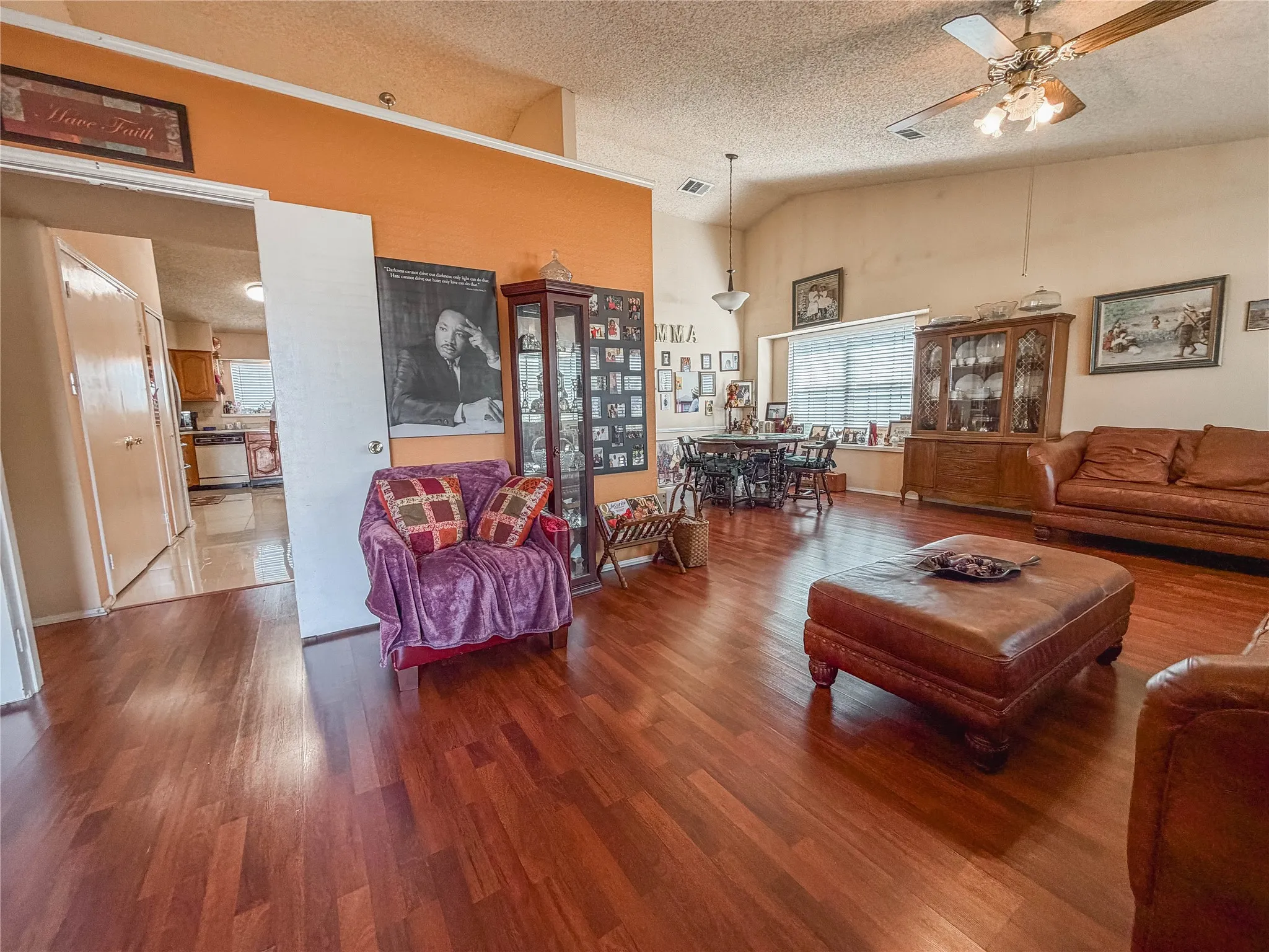Wood-finish flooring throughout, vaulted ceiling, built-in ceiling fan, window with blinds, and transom window