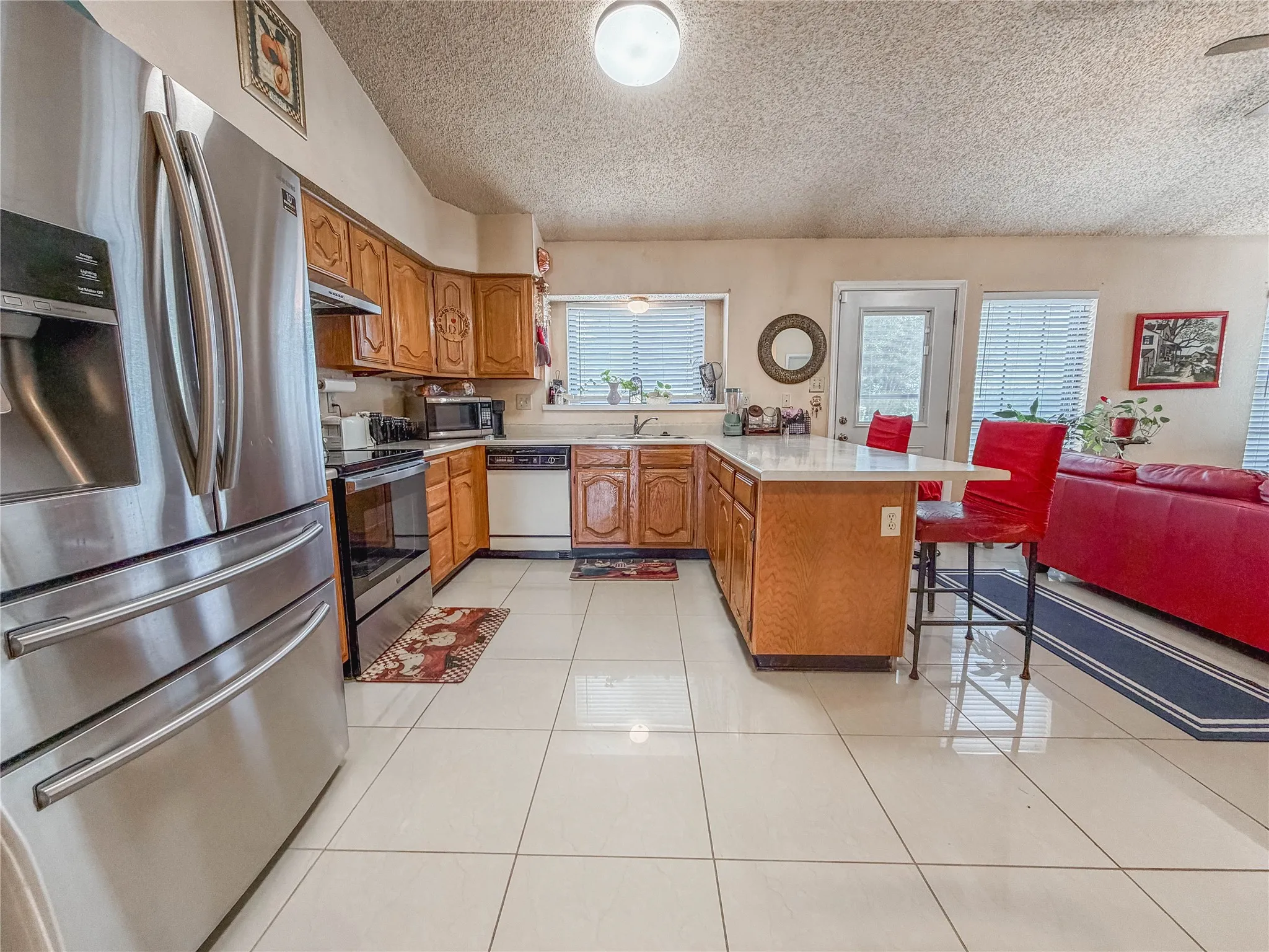 Kitchen featuring wood cabinetry, stainless steel refrigerator, white countertops, and white tile flooring