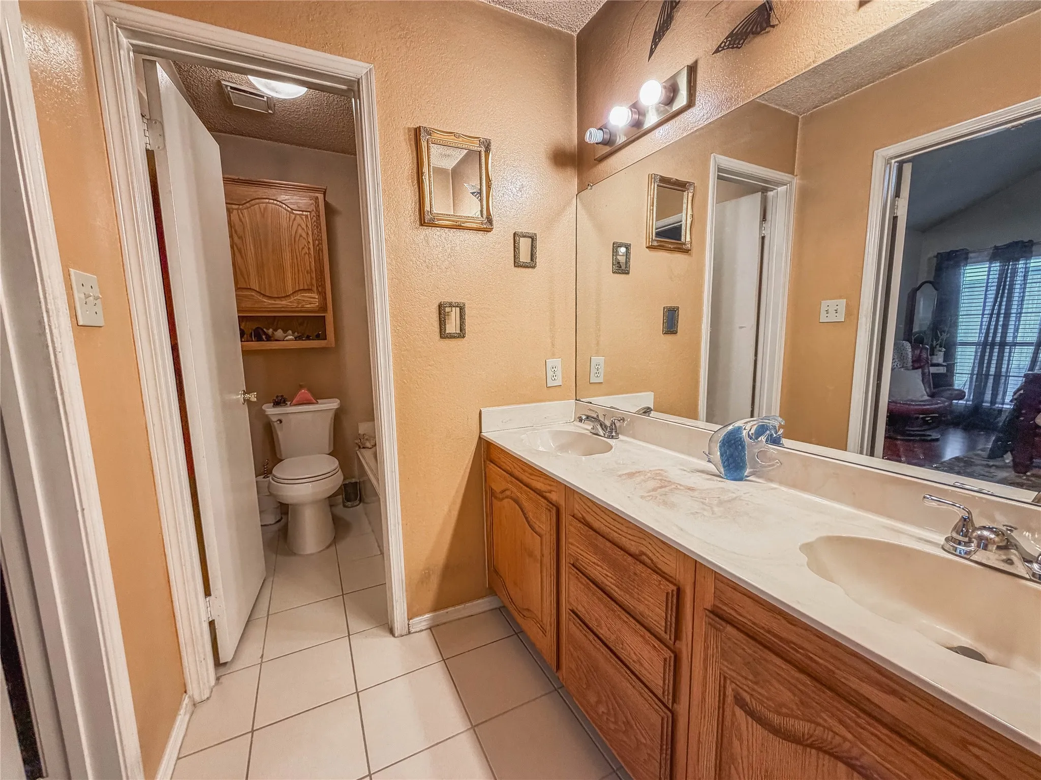 Double vanity with wood-finish cabinetry, integrated sinks, and polished chrome fixtures