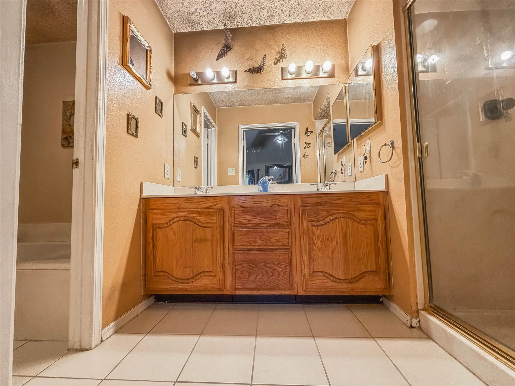 Double vanity with wood-finish cabinetry and dual mirrors, set on tile flooring