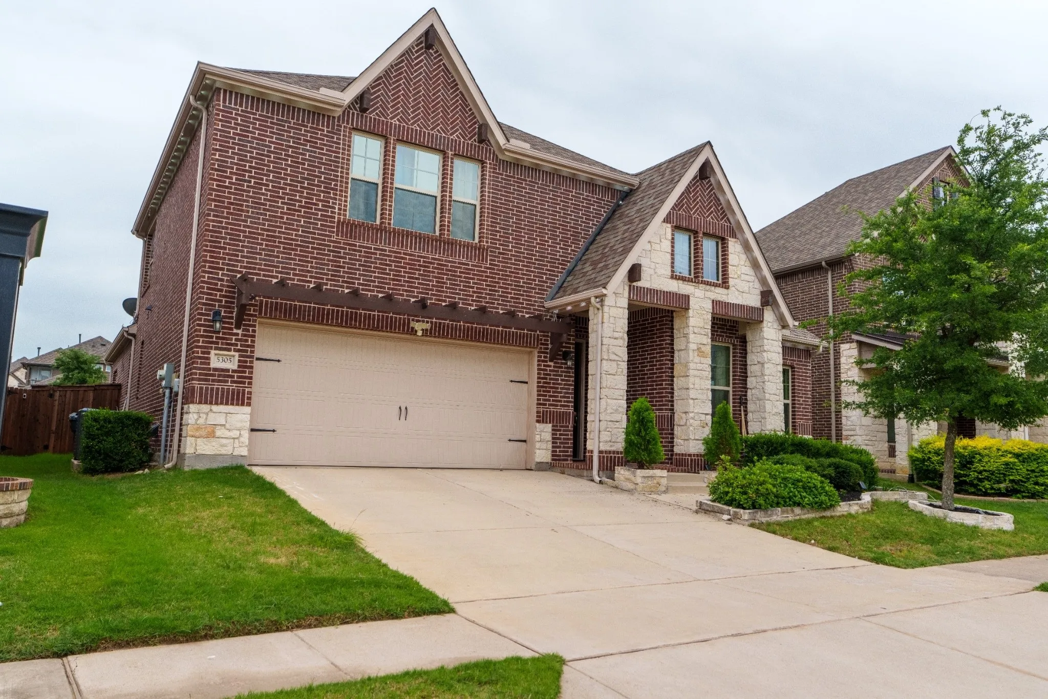 Traditional two-story residence featuring a brick facade with stone accents