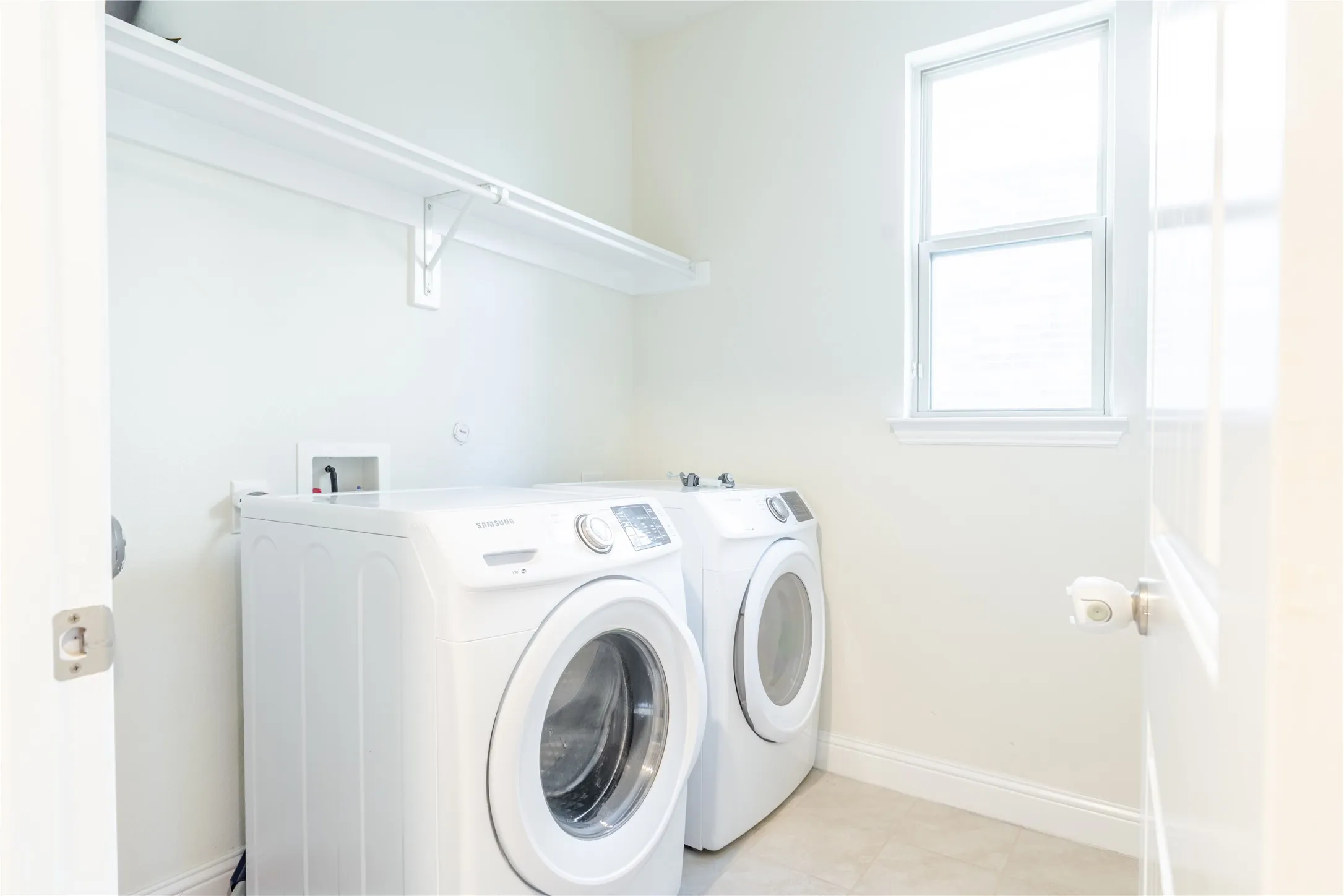 Dedicated utility space featuring a window, built-in shelving, and light-toned tile flooring