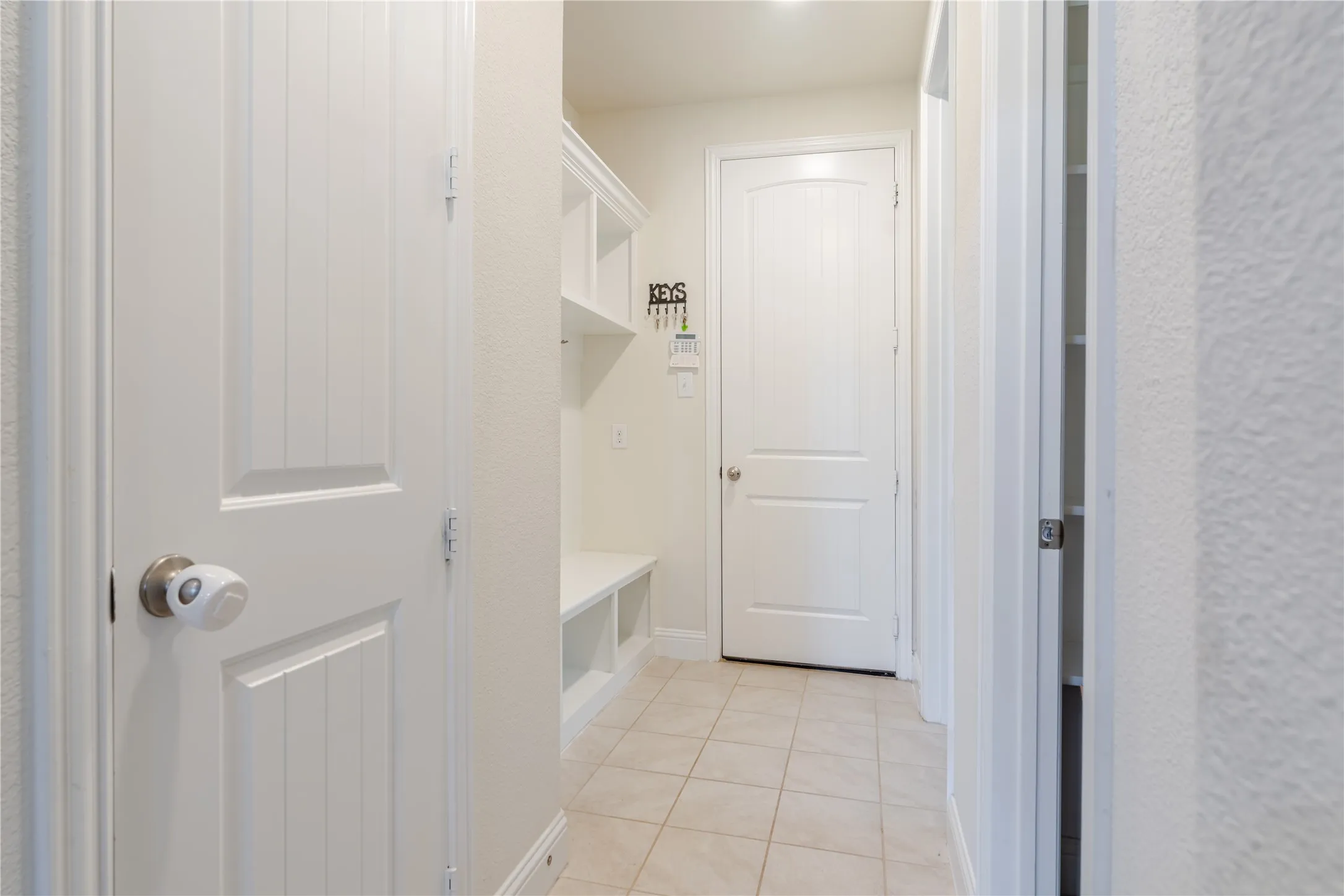 Hallway featuring built-in shelving, a storage bench, and ceramic tile flooring