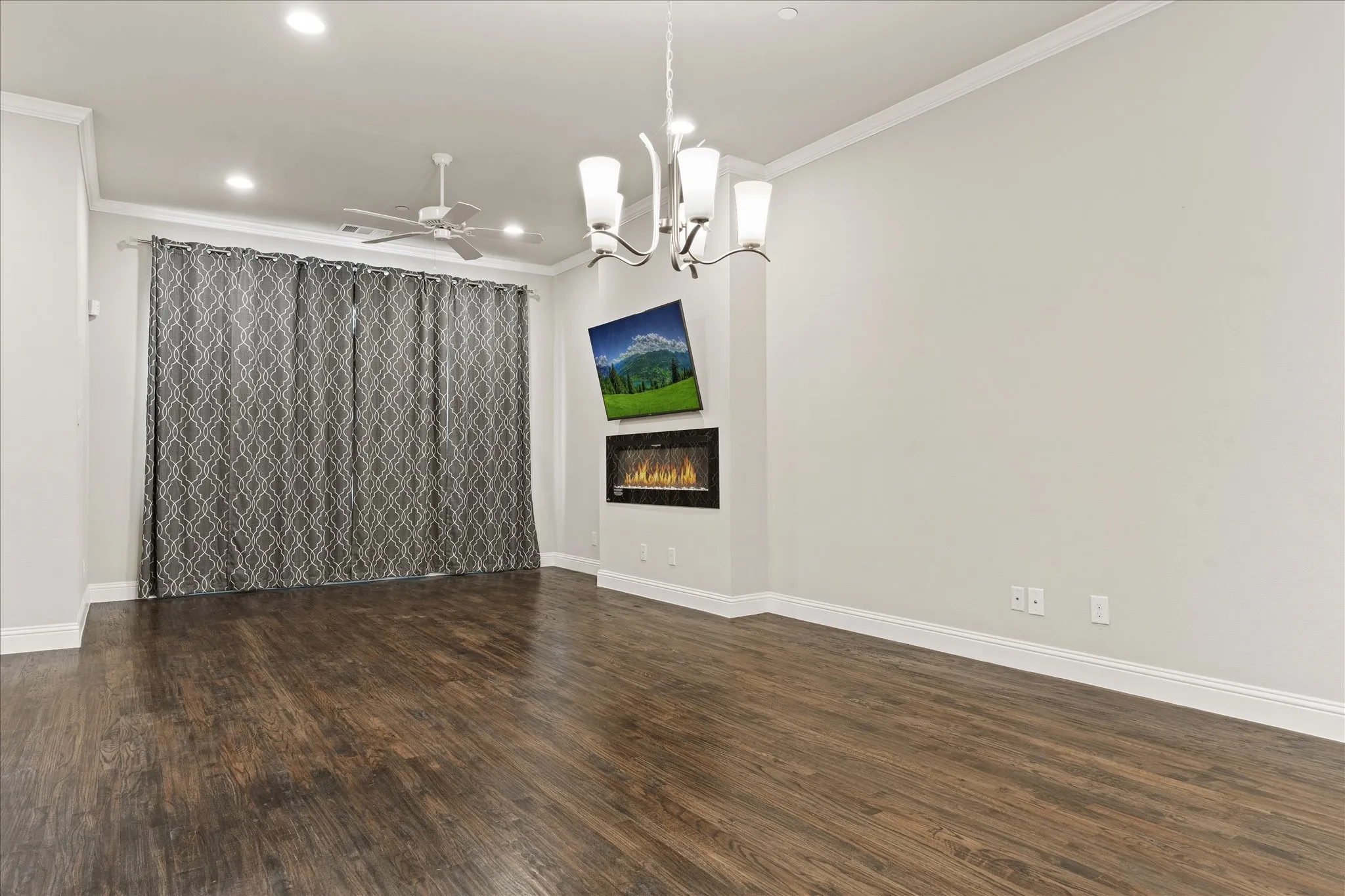 Wood-finish flooring, recessed lighting, crown molding, built-in electric fireplace, and a ceiling fan