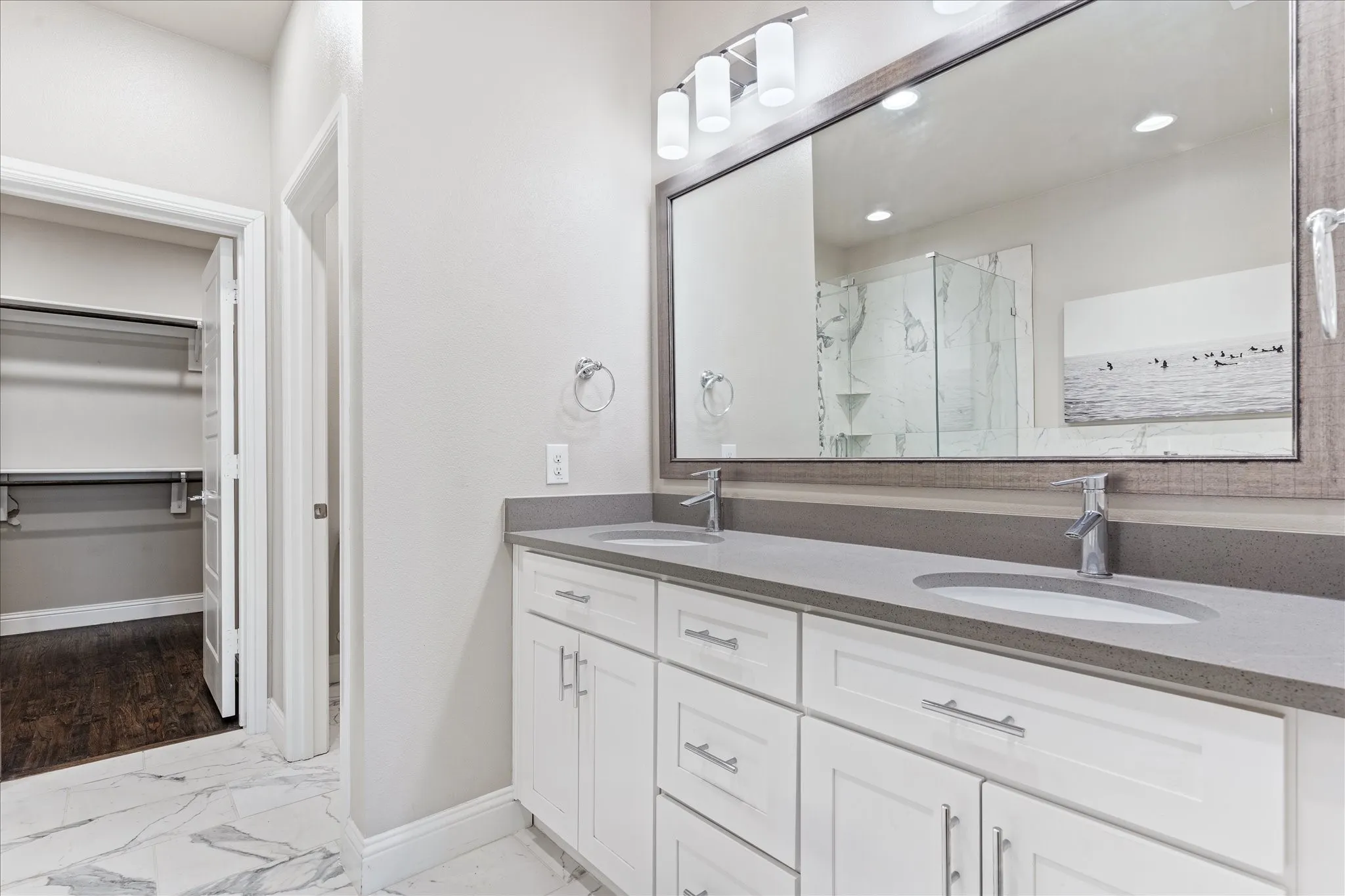 Dual vanity with gray countertops, white cabinetry, undermount sinks, and a framed mirror