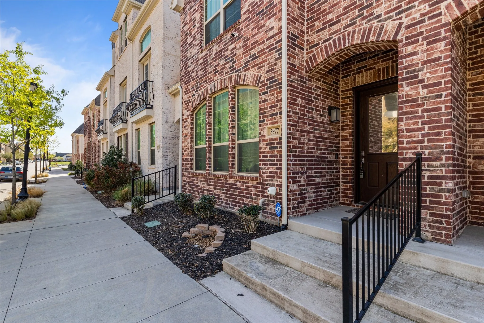Red brick exterior with arched window detailing and a dark wood-finish entry door