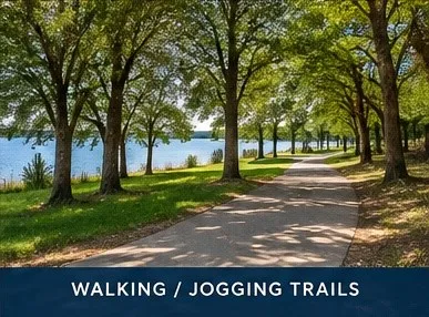 Paved recreational pathway lined with mature trees, situated alongside a body of water
