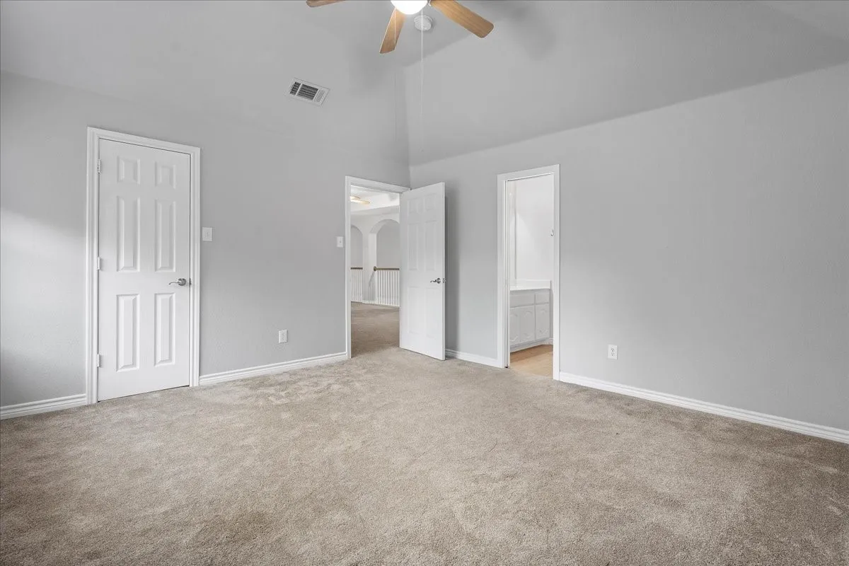 Carpeted room with vaulted ceiling and ceiling fan