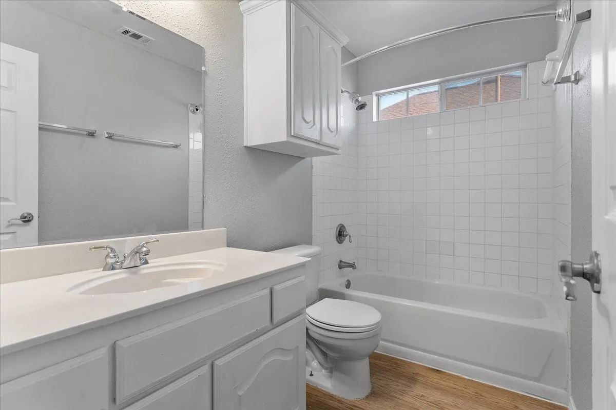 Bathroom featuring a white vanity with an integrated sink, chrome fixtures, and a frameless mirror
