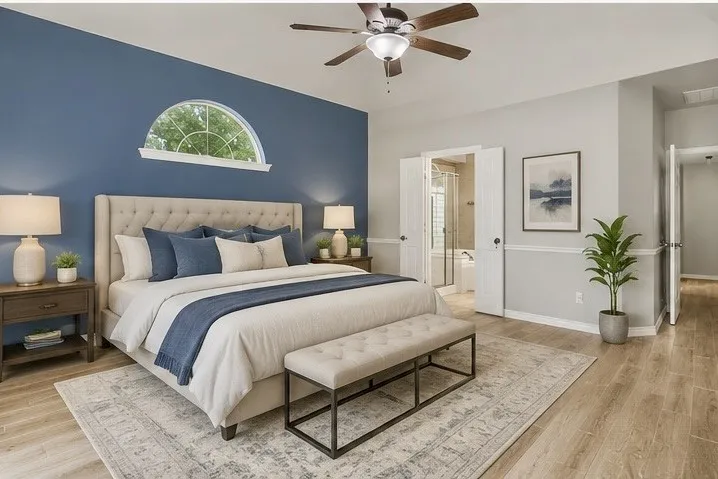 Expansive bedroom featuring an arched transom window, wood-finish flooring, and a ceiling fan with integrated lighting