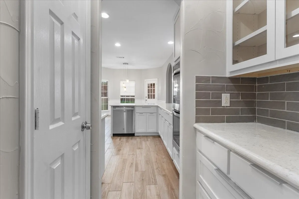 Kitchen featuring wood-finish flooring, white cabinetry, a subway tile backsplash, stainless steel appliances, and recessed lighting