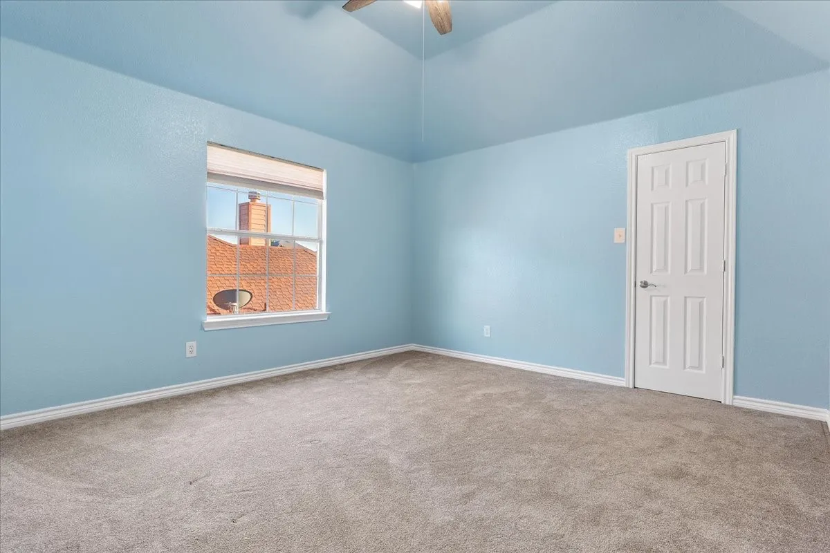 Spacious room featuring vaulted ceilings, light blue wall paint, and plush carpet flooring