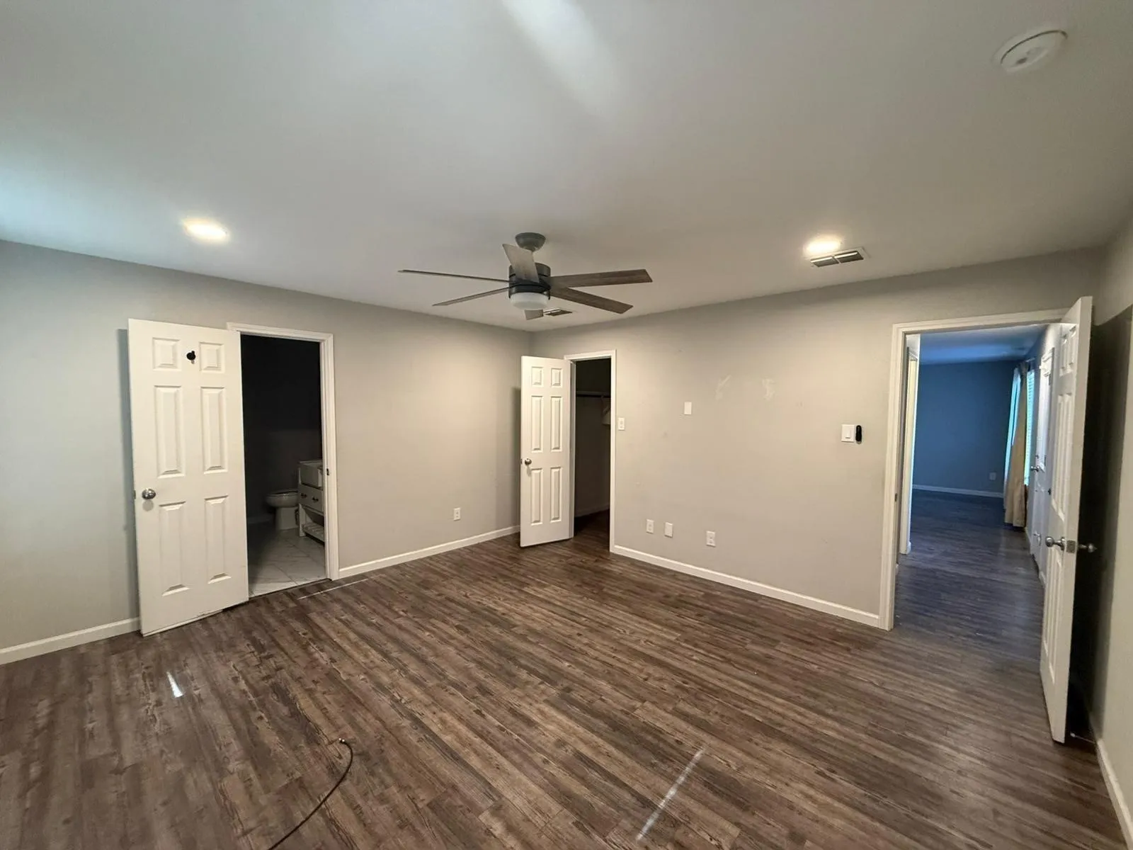 Wood-finish flooring, ceiling fan with integrated lighting, recessed lighting, and white interior doors