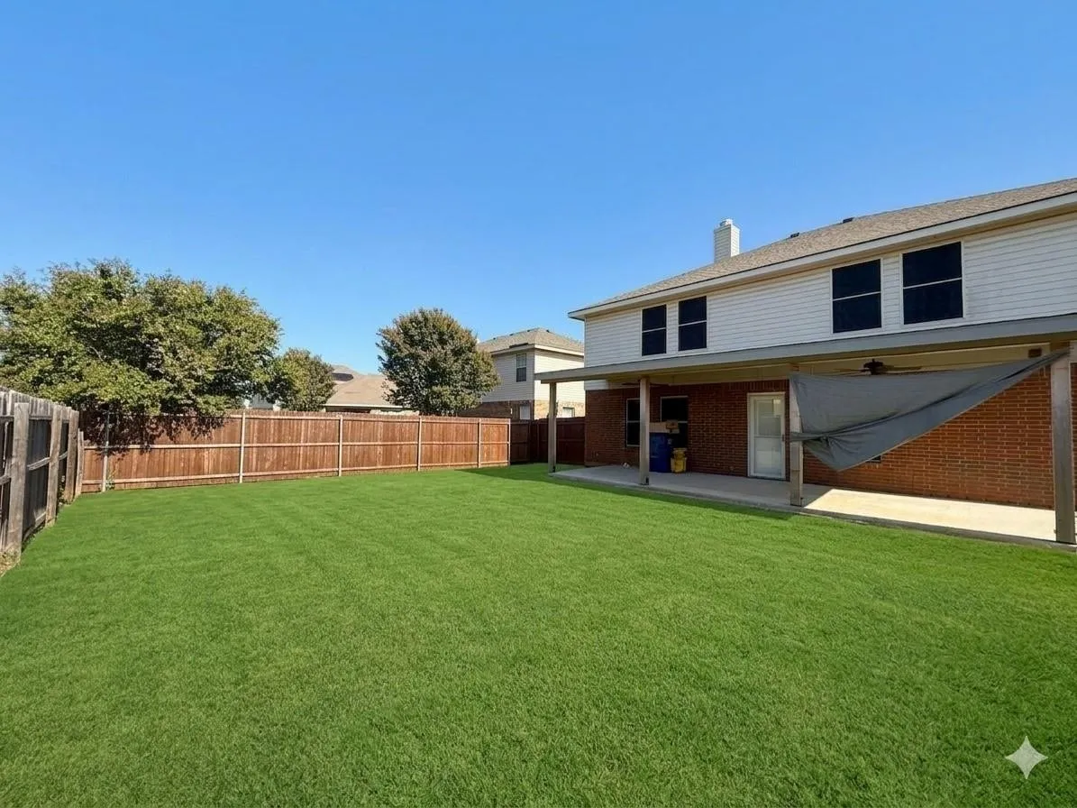 Expansive backyard with a manicured lawn, a full wooden privacy fence, and a covered patio with a concrete slab