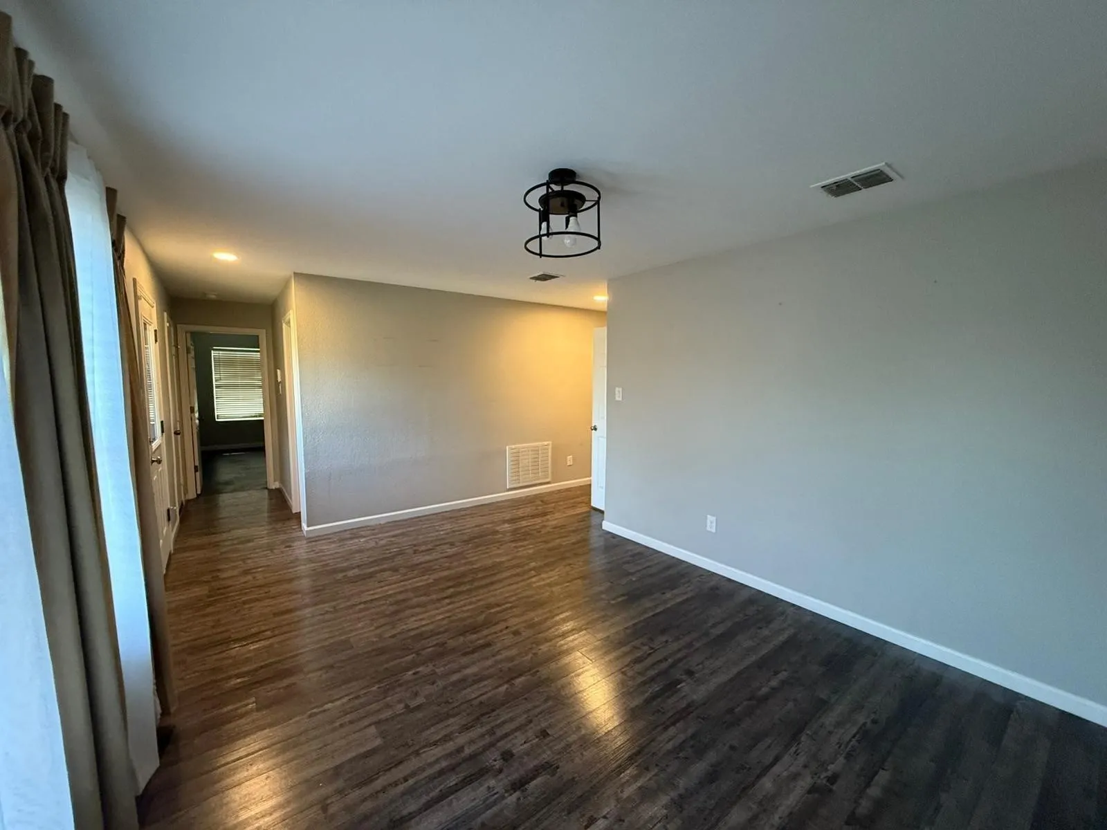 Dark wood-finish flooring with light-toned wall paint and an industrial-style ceiling light fixture