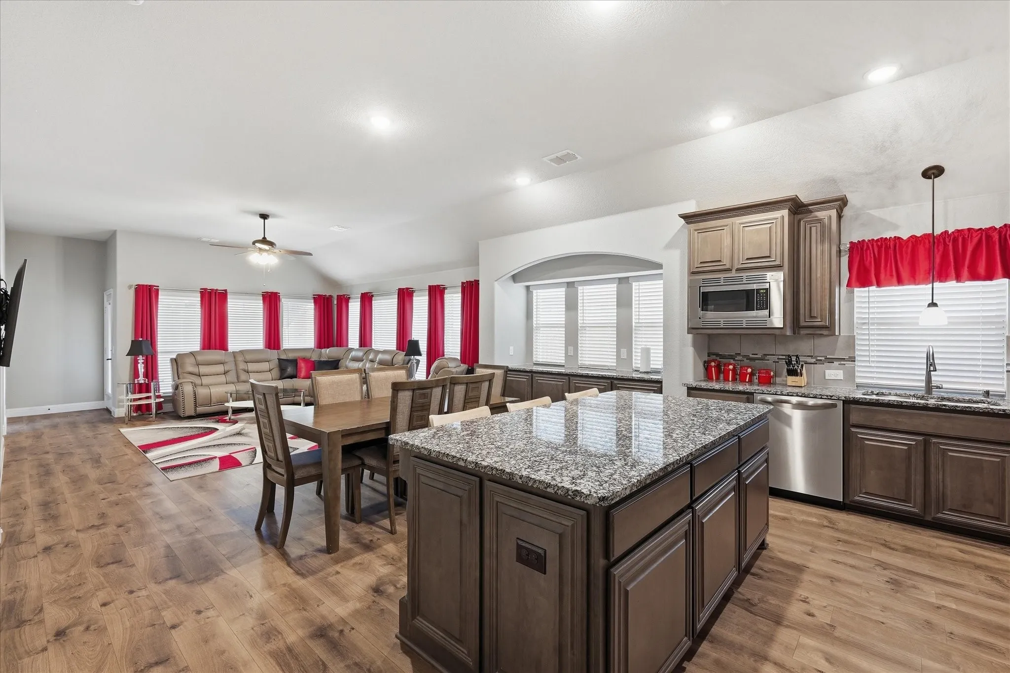 Open-concept design featuring wood-finish flooring, a kitchen island with stone countertop, stainless steel appliances, and recessed lighting