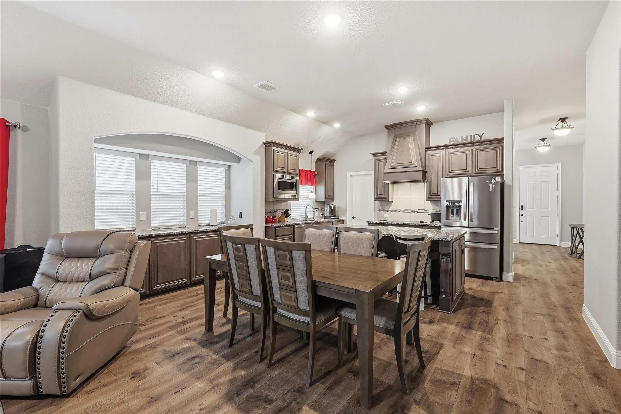 Open-concept living area featuring wood-finish flooring, recessed lighting, and an arched architectural detail