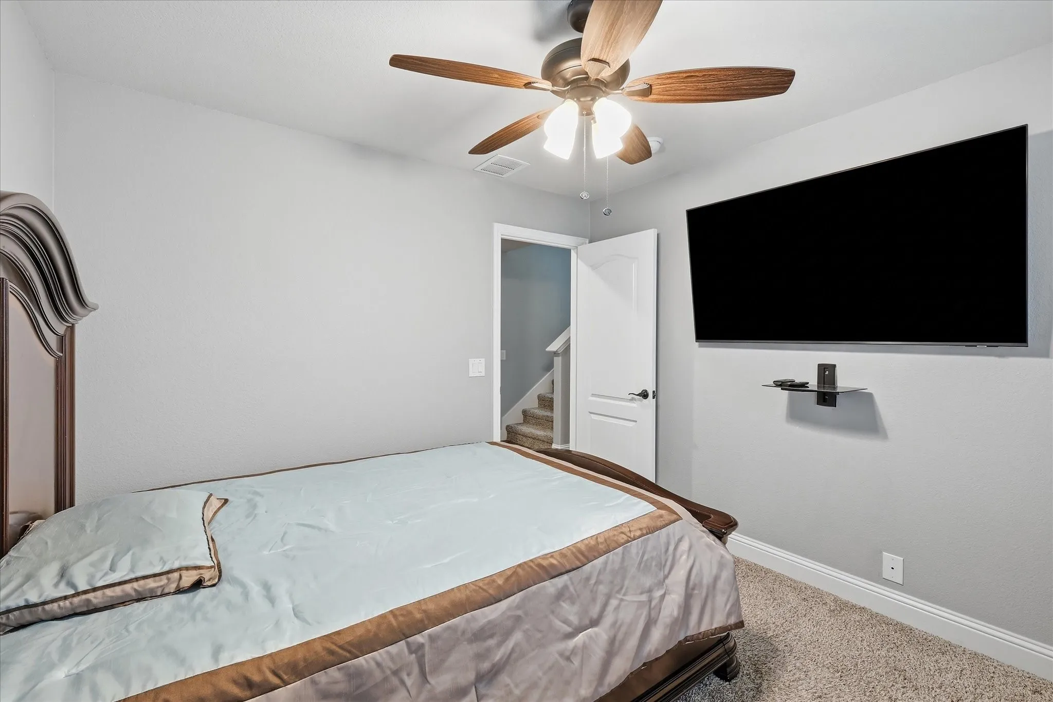 Recessed ceiling fan with wood-finish blades, wall-mounted display, and carpeted flooring