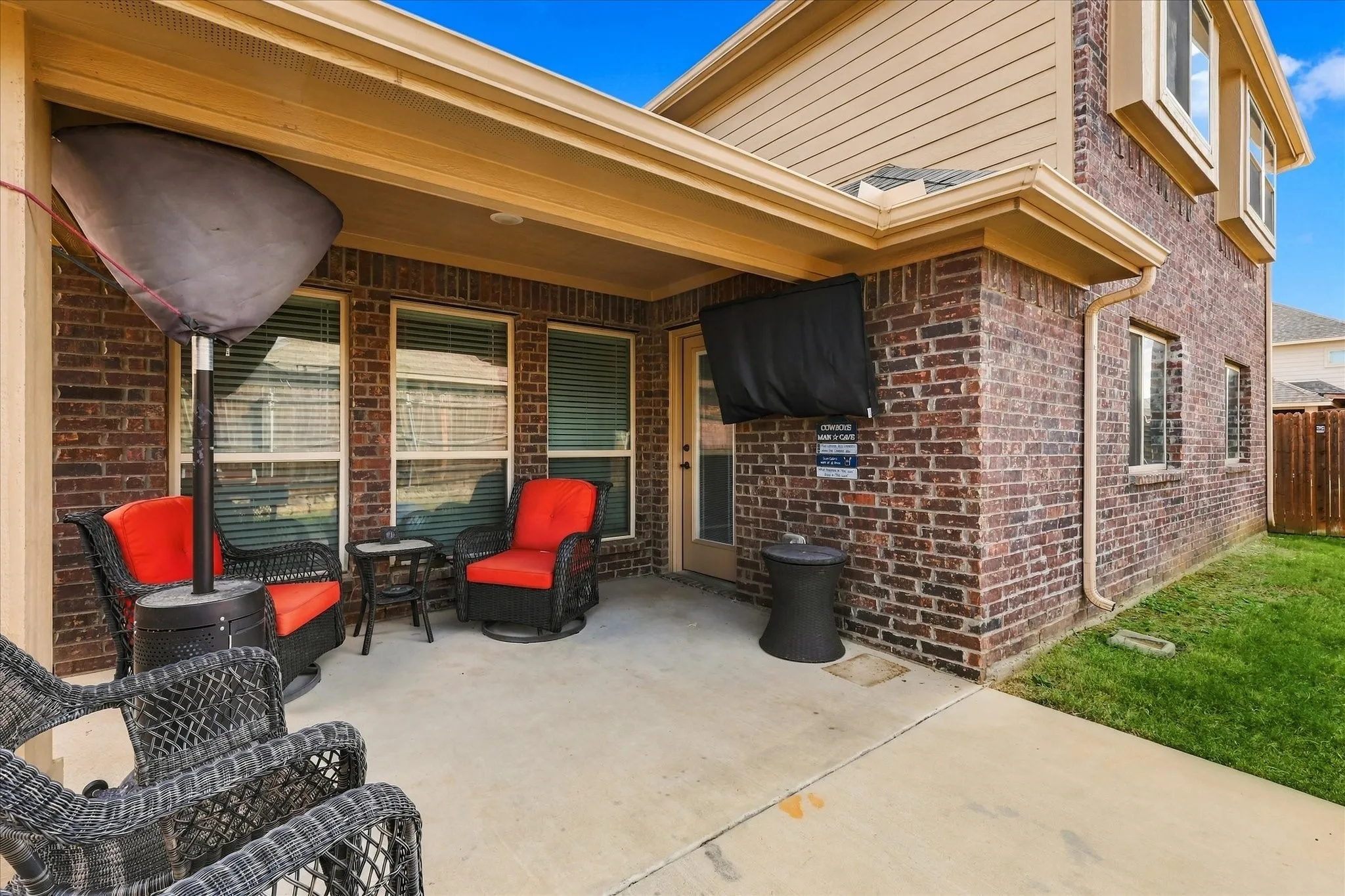 Covered patio featuring a concrete surface, brick exterior, and multiple windows with blinds