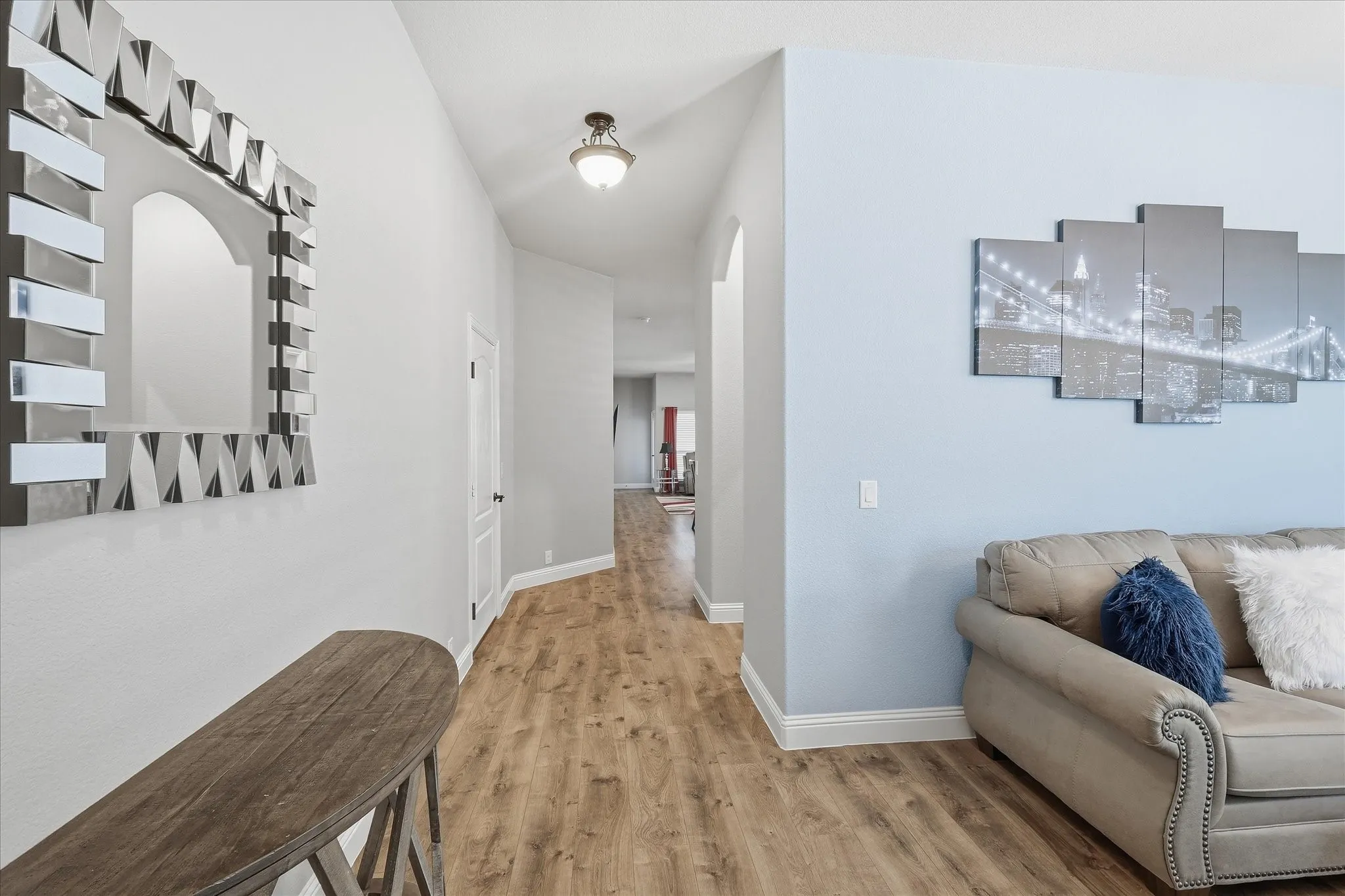 Wood-finish flooring throughout, light neutral wall paint, and a classic flush mount ceiling light fixture