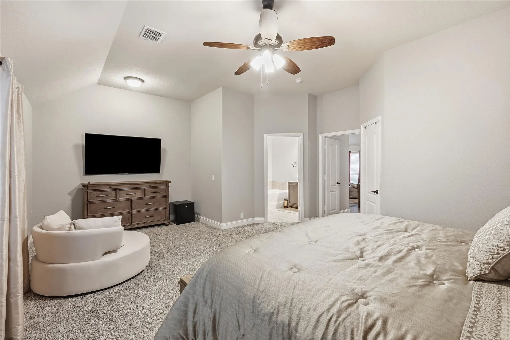 Vaulted ceiling featuring a ceiling fan, plush carpet flooring, and light-colored wall paint