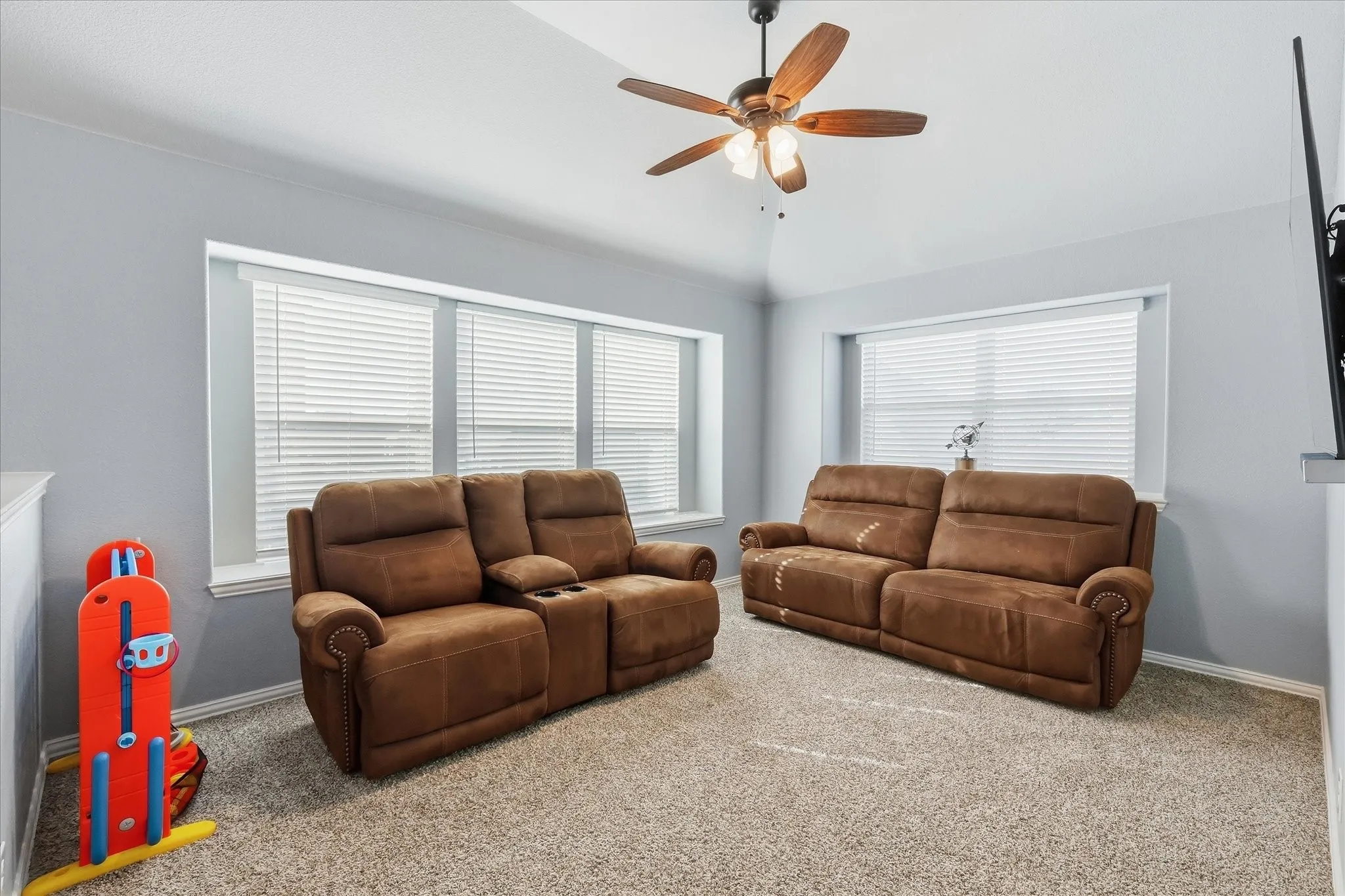 Carpet flooring, multiple windows with blinds, pitched ceiling, and a ceiling fan with integrated lighting