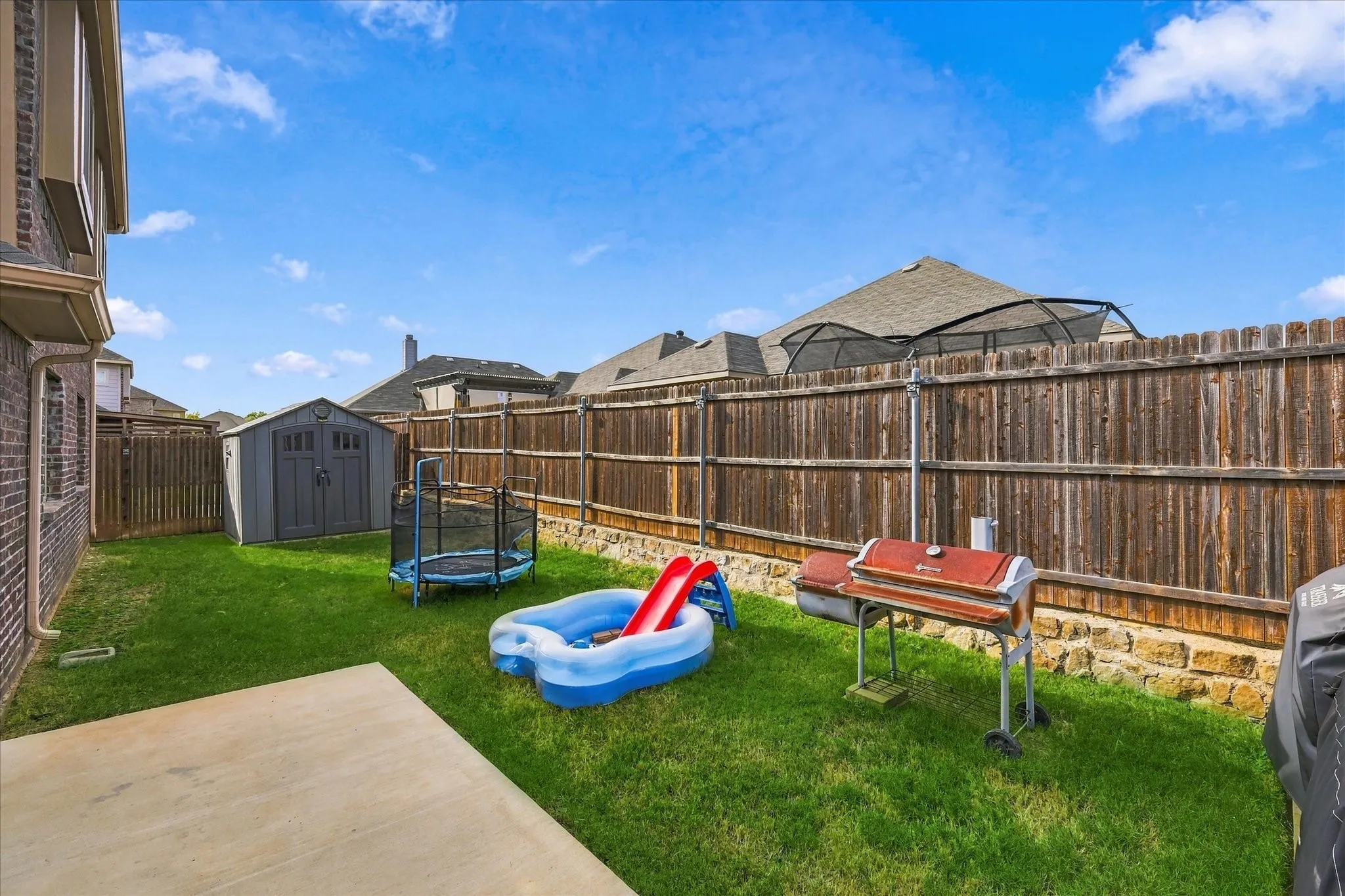 Expansive grassy yard with wood fencing and stone base