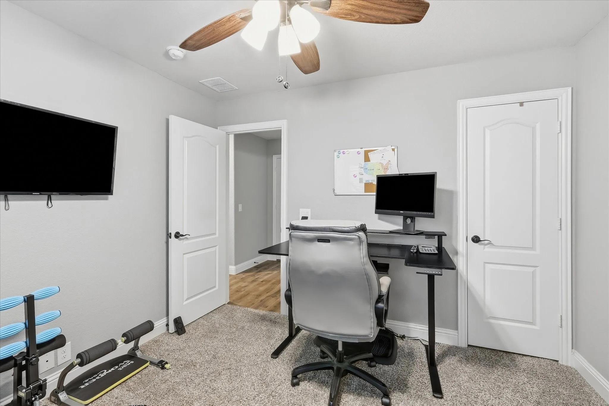 Carpeted room with light gray walls, white trim, and a ceiling fan with wood-finish blades