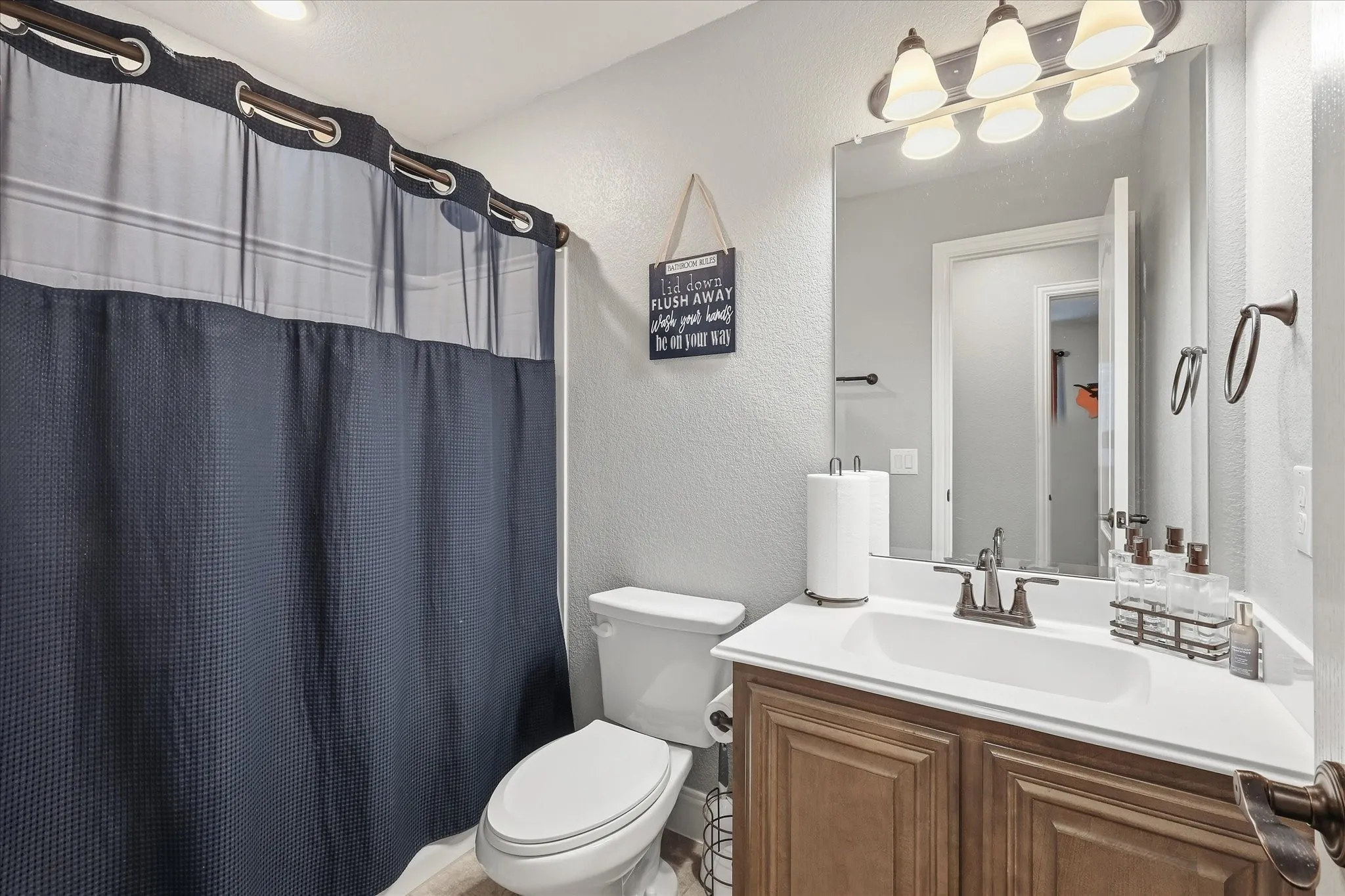 Spa-inspired bathroom featuring a wood-finish vanity with dual-sink configuration, white quartz countertop, and brushed nickel fixtures
