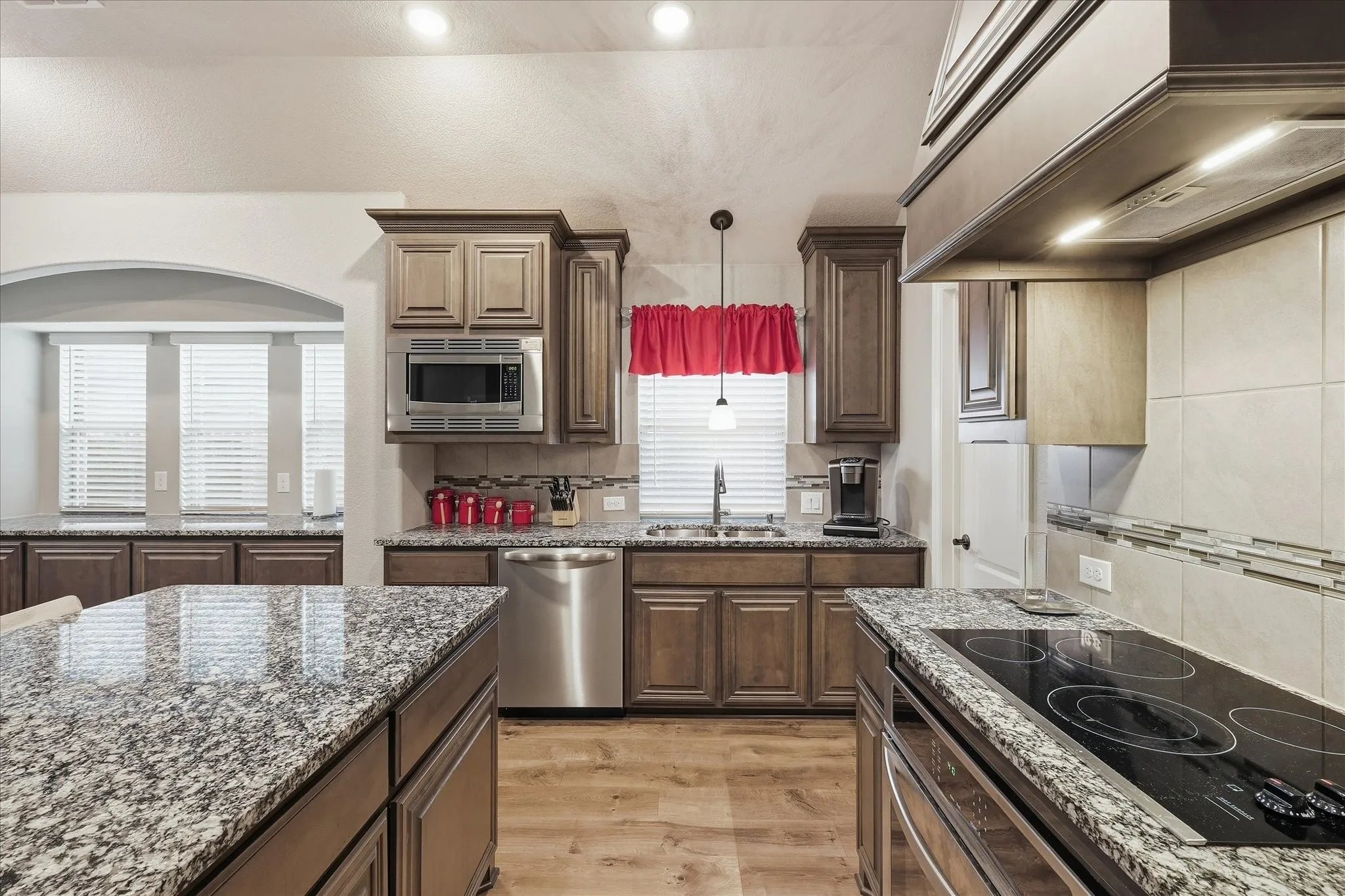 Kitchen featuring granite countertops, wood-finish flooring, stainless steel appliances, recessed lighting, and built-in cabinetry
