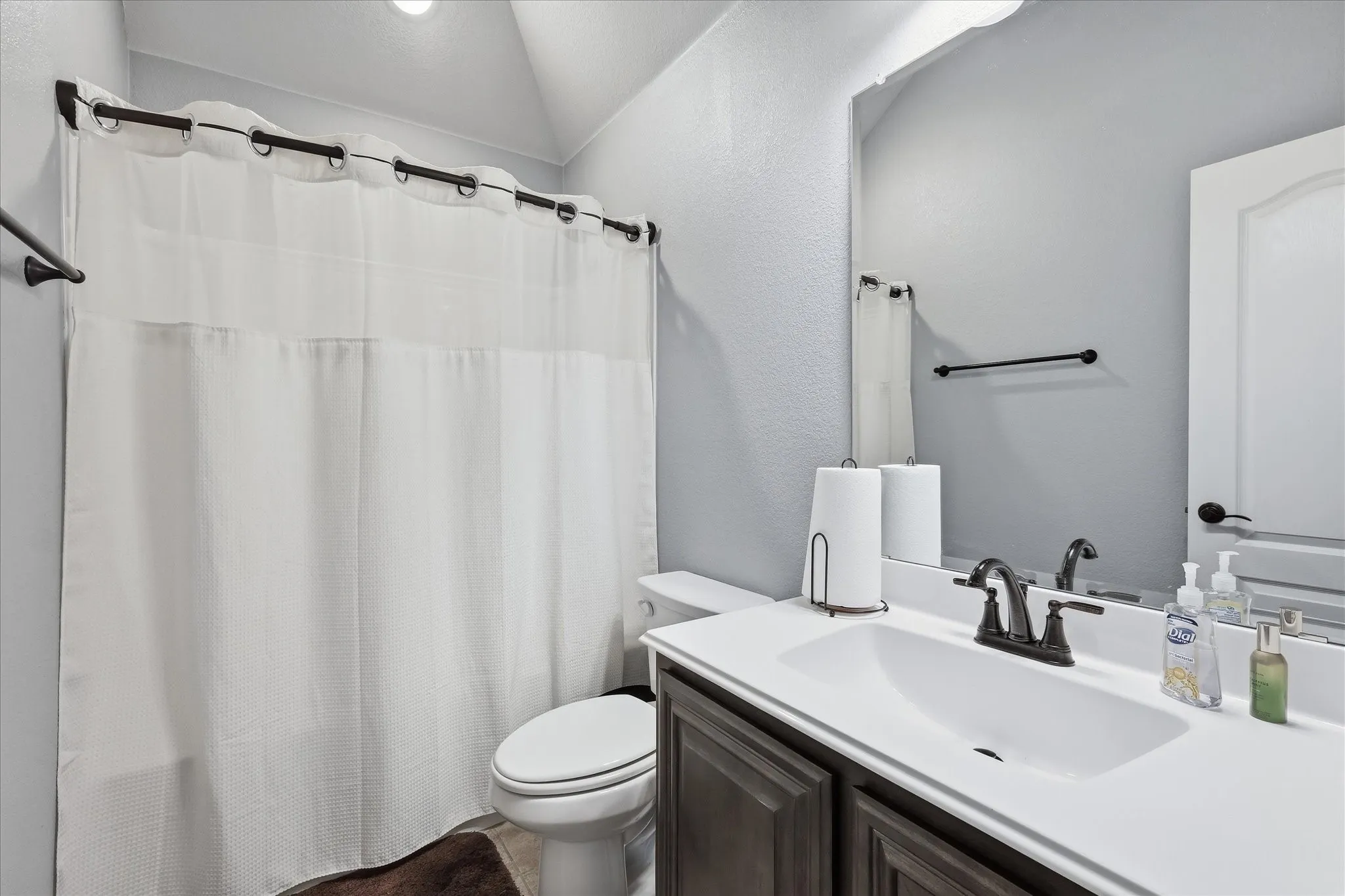 Bathroom featuring a single vanity with dark cabinetry, integrated sink, and dark bronze-finish fixtures