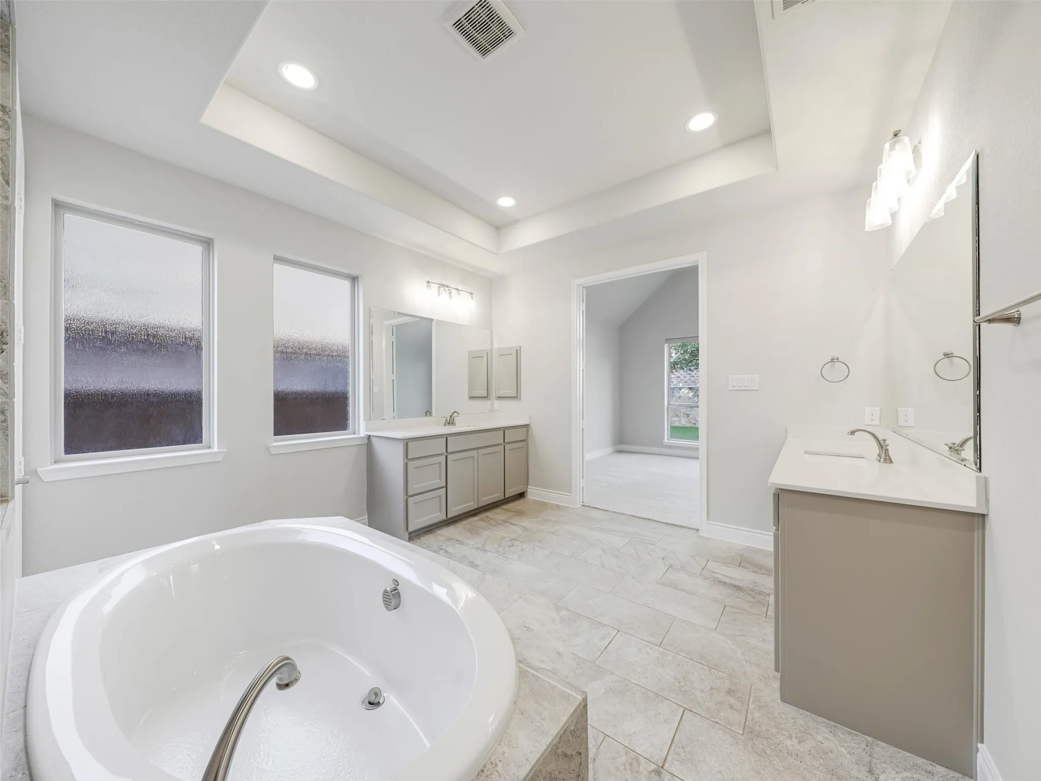 The ensuite bathroom is thoughtfully arranged with dual vanities, a soaking tub, separate shower, linen closet, and two walk-in closets, providing generous storage and personal space. An especially convenient feature is the direct access from the primary bath to the laundry room, creating an efficient connection between the home's everyday living spaces.