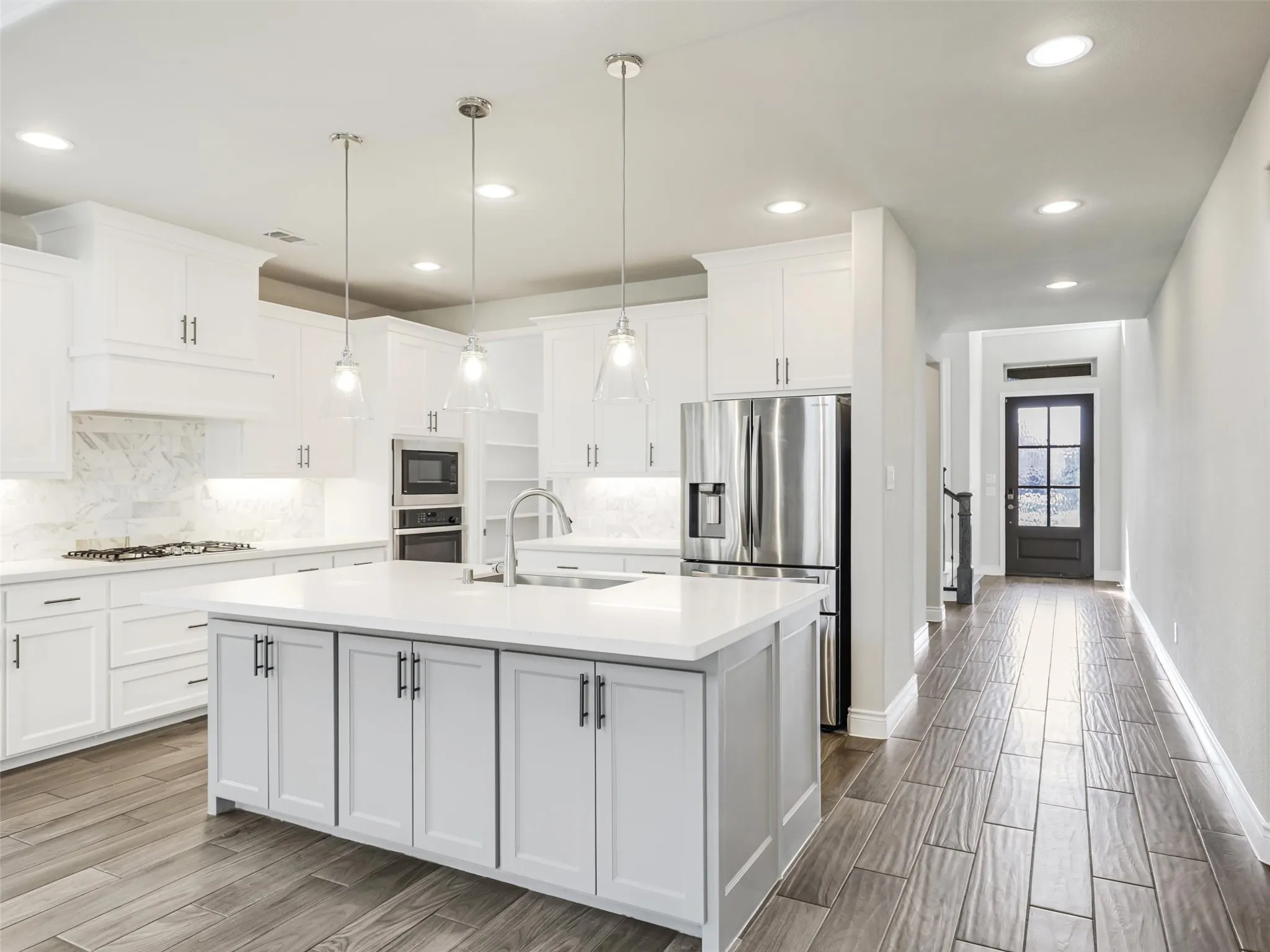 At the heart of the home is a well-appointed kitchen that seamlessly connects to the main living areas. Stainless steel appliances are complemented by a gas cooktop and built-in microwave, while a spacious walk-in pantry provides plenty of room for groceries, small appliances, and additional storage. A large center island with breakfast bar seating creates a natural gathering place for casual meals, morning coffee, or conversation while entertaining.