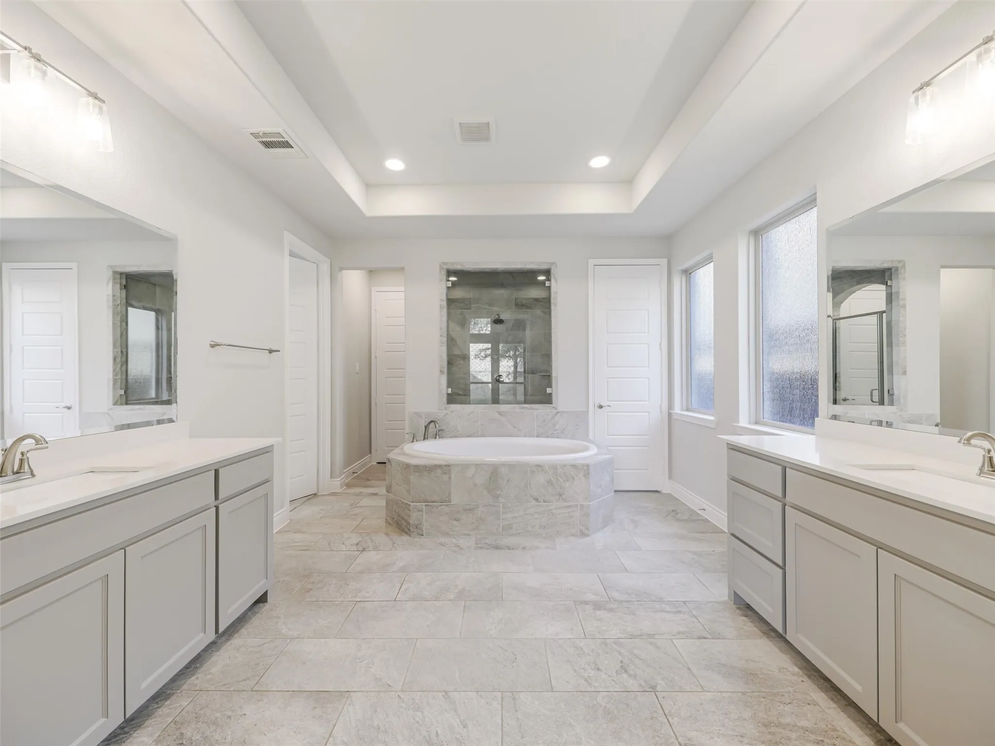 The ensuite bathroom is thoughtfully arranged with dual vanities, a soaking tub, separate shower, linen closet, and two walk-in closets, providing generous storage and personal space. An especially convenient feature is the direct access from the primary bath to the laundry room, creating an efficient connection between the home's everyday living spaces.