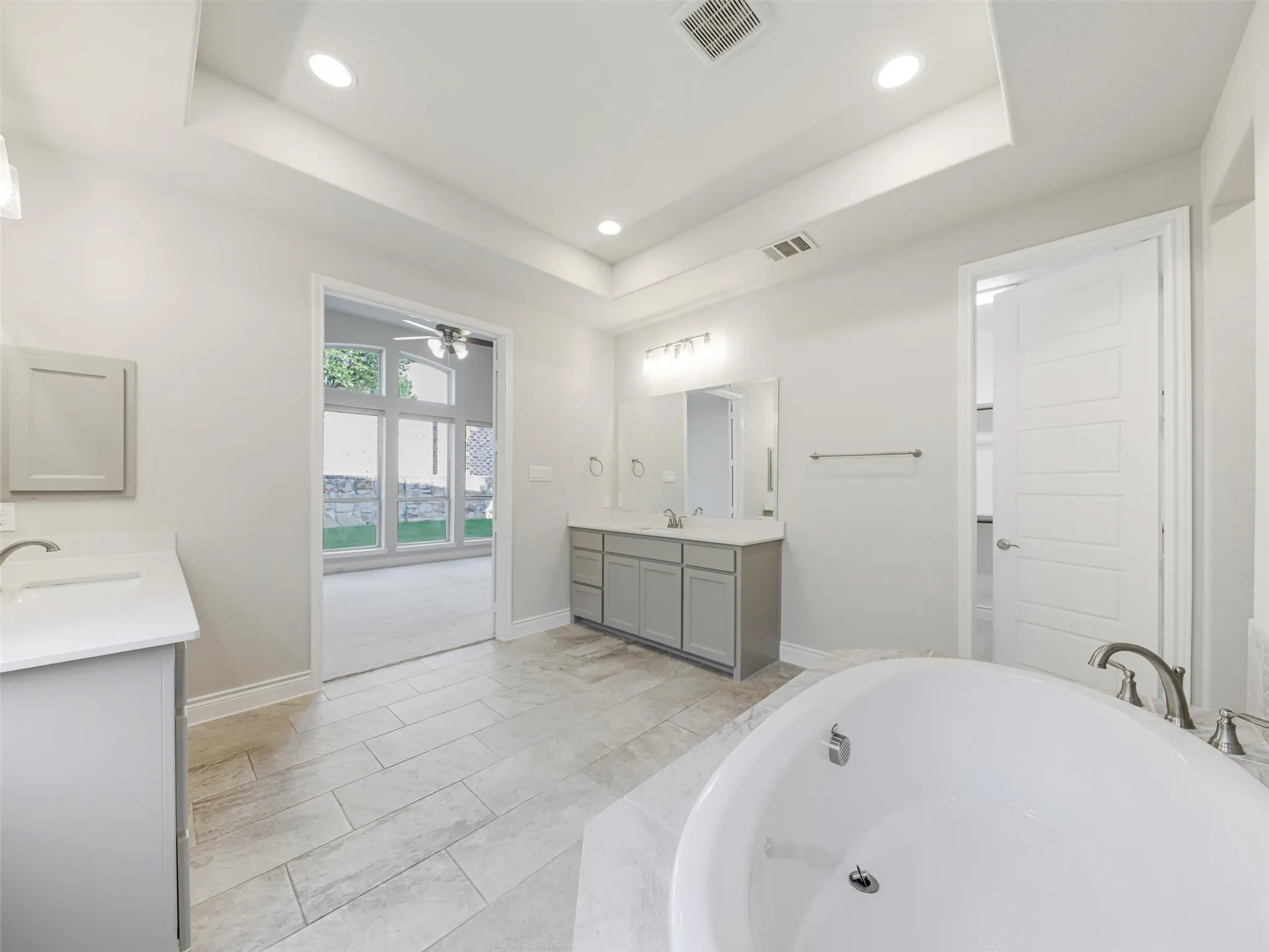 The ensuite bathroom is thoughtfully arranged with dual vanities, a soaking tub, separate shower, linen closet, and two walk-in closets, providing generous storage and personal space. An especially convenient feature is the direct access from the primary bath to the laundry room, creating an efficient connection between the home's everyday living spaces. The laundry room accommodates full-size washer and dryer connections and is conveniently positioned for easy access from the primary suite.