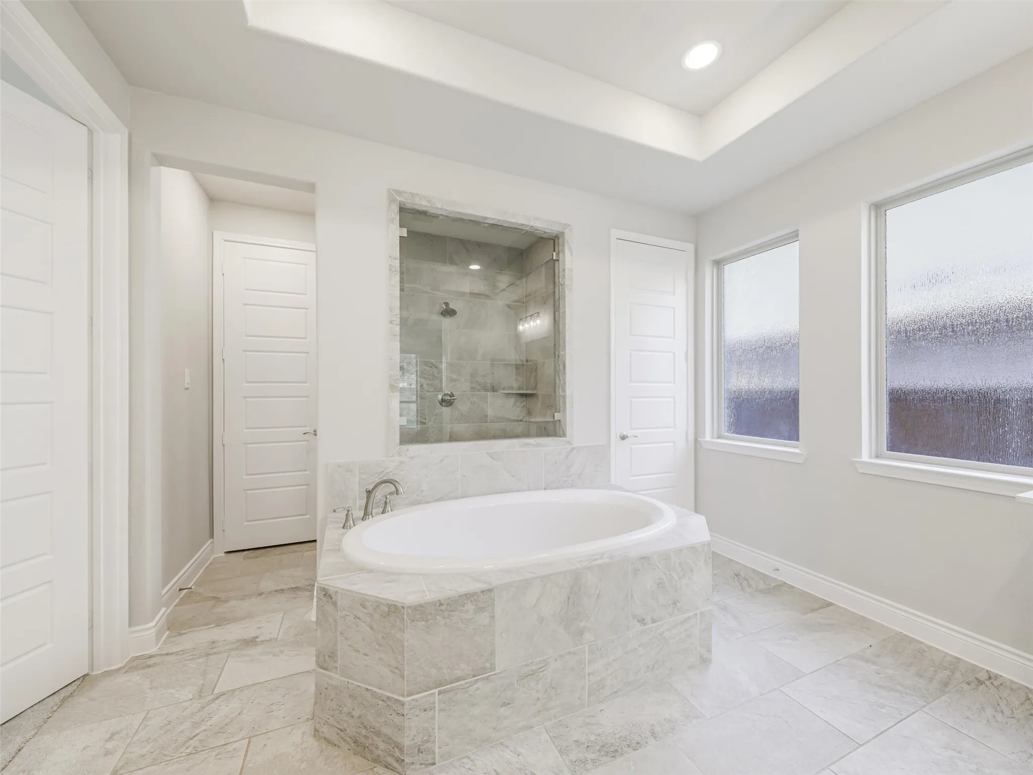The ensuite bathroom is thoughtfully arranged with dual vanities, a soaking tub, separate shower, linen closet, and two walk-in closets, providing generous storage and personal space. An especially convenient feature is the direct access from the primary bath to the laundry room, creating an efficient connection between the home's everyday living spaces. The laundry room accommodates full-size washer and dryer connections and is conveniently positioned for easy access from the primary suite.