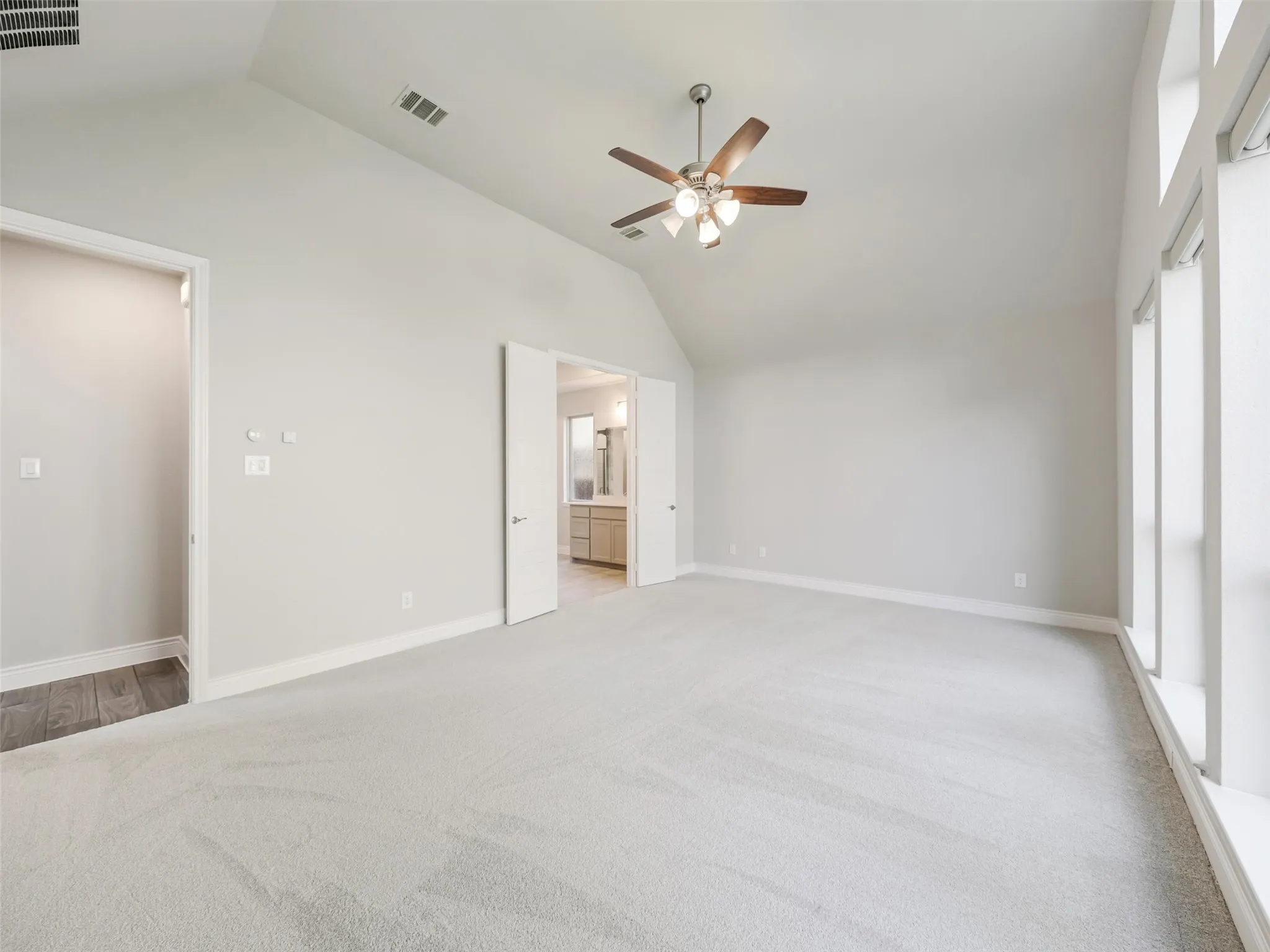 The primary suite provides a spacious retreat with a vaulted ceiling and abundant natural light.
