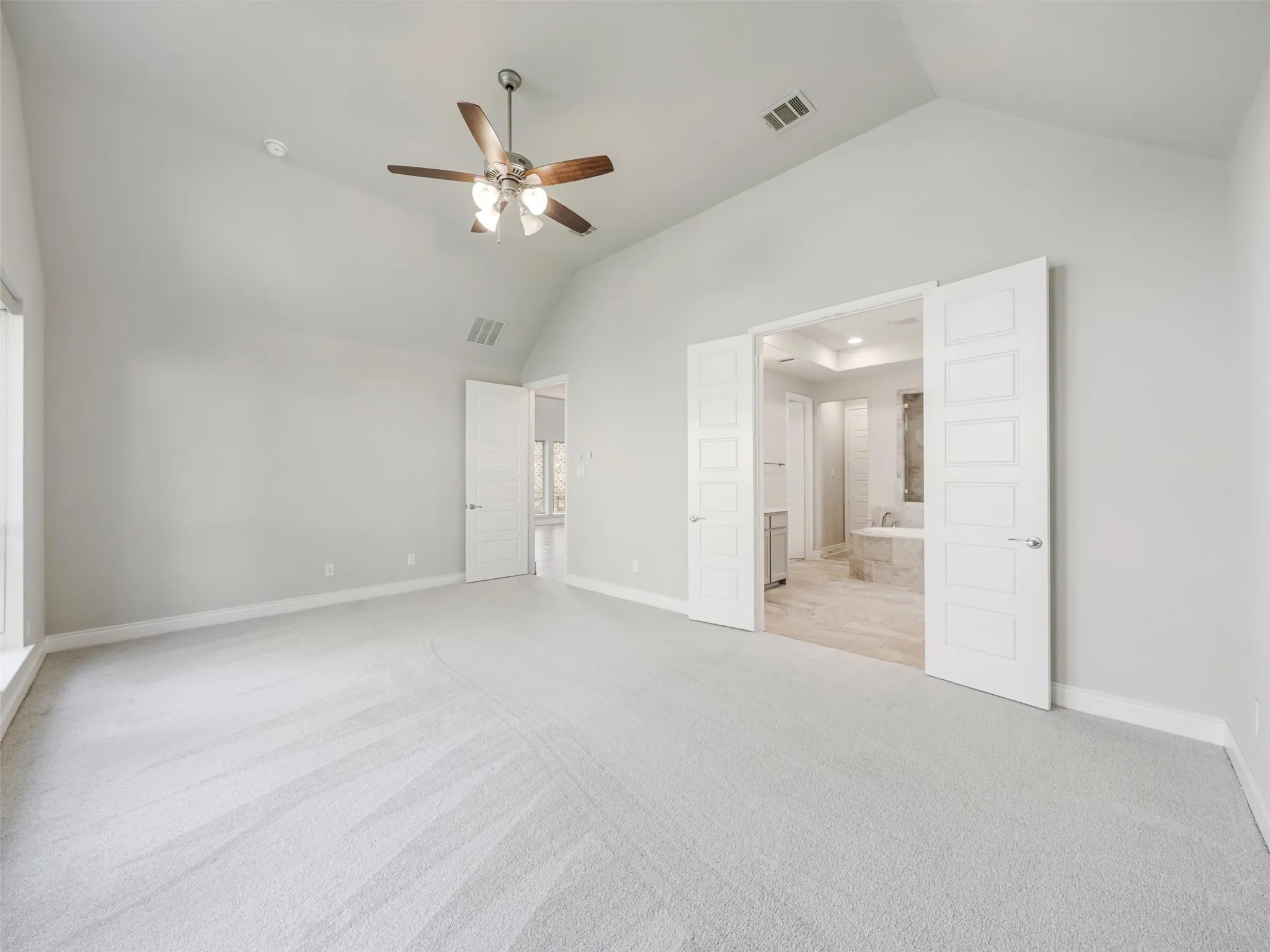The primary suite provides a spacious retreat with a vaulted ceiling and abundant natural light.