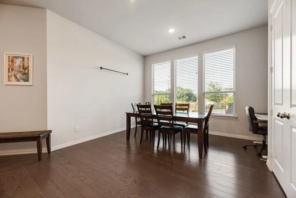 Spacious interior room featuring wood-finish flooring, white baseboards, and light neutral wall colors