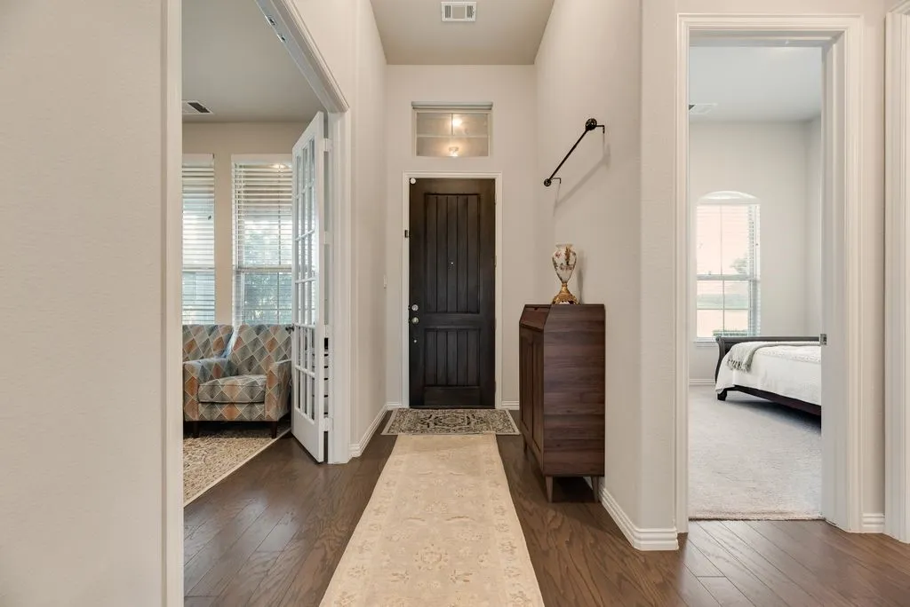 Entryway featuring wood-finish flooring, a dark wood paneled door with transom window, and white trim